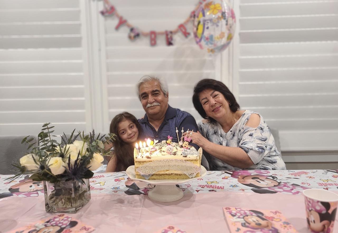 A group of people sitting at a table with a cake