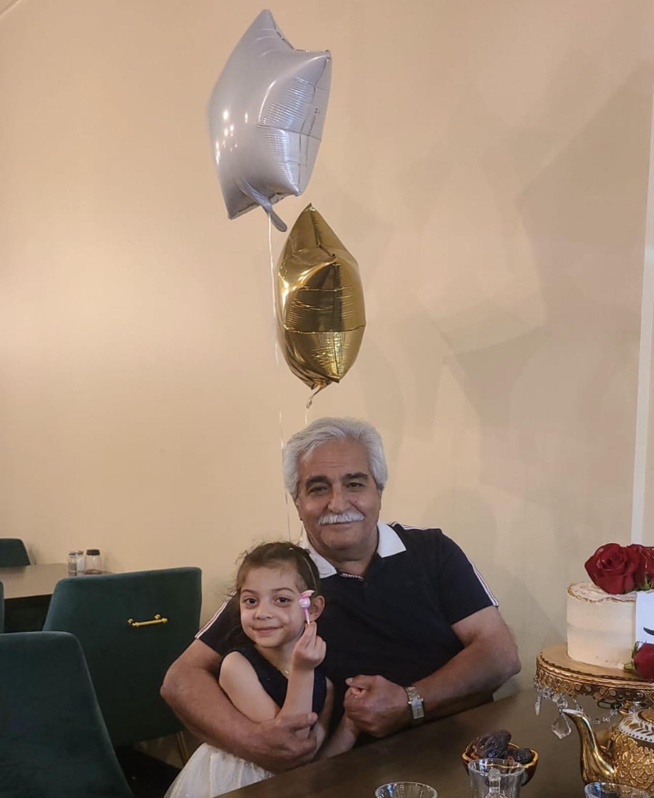A man and girl sitting at a table with balloons