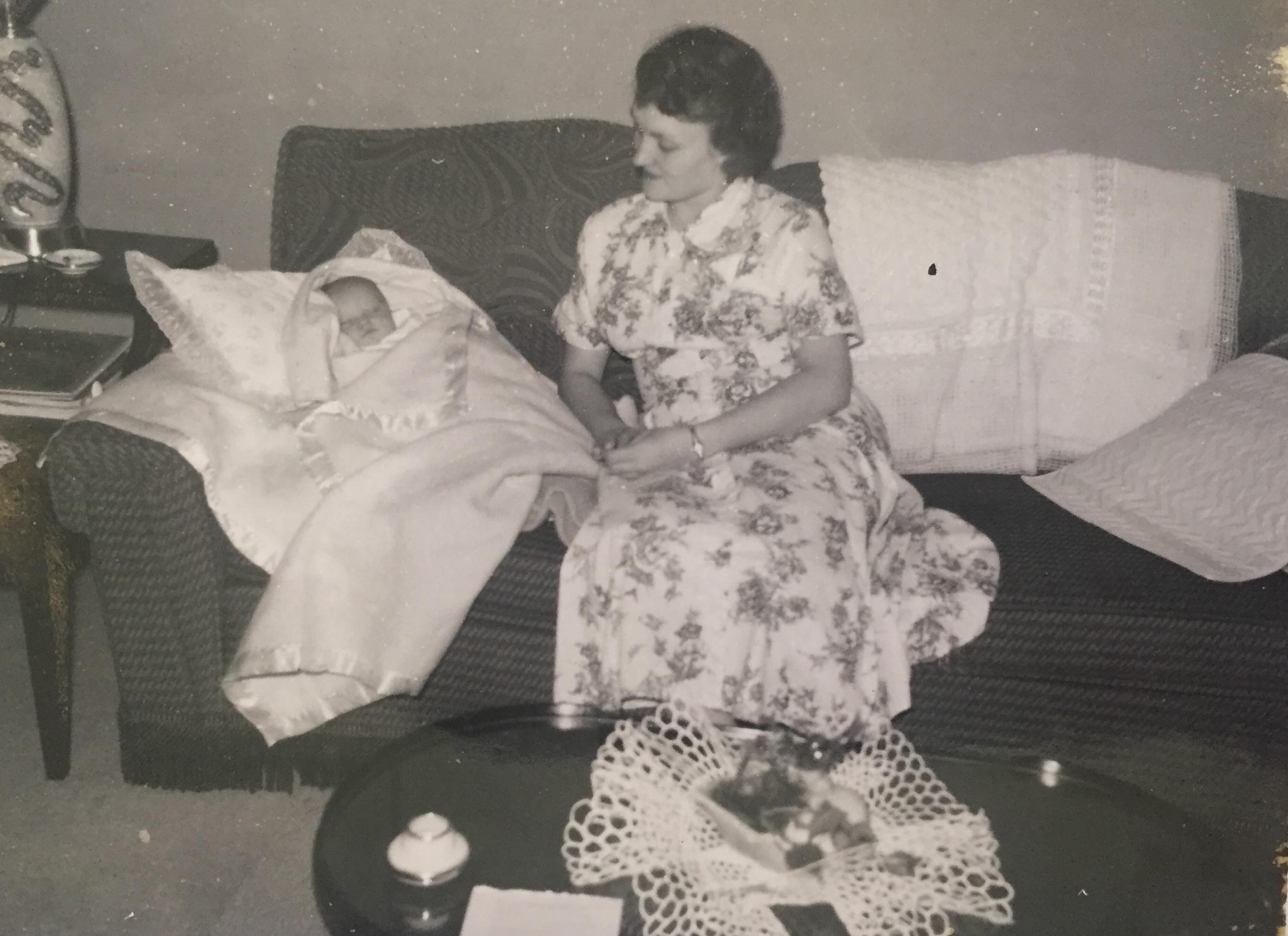 A woman sitting on a couch holding a baby