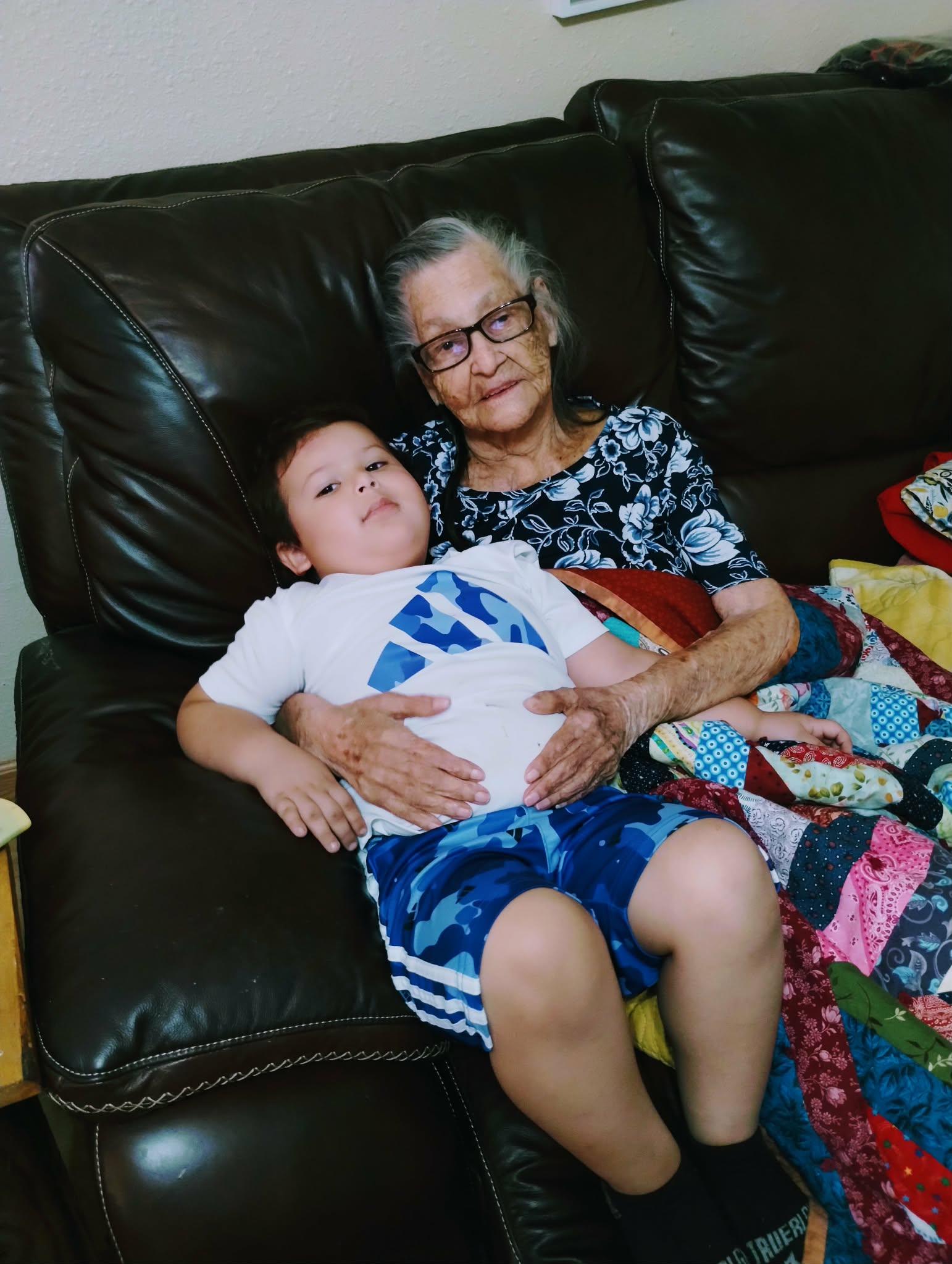 An old woman and a young boy sitting on a couch