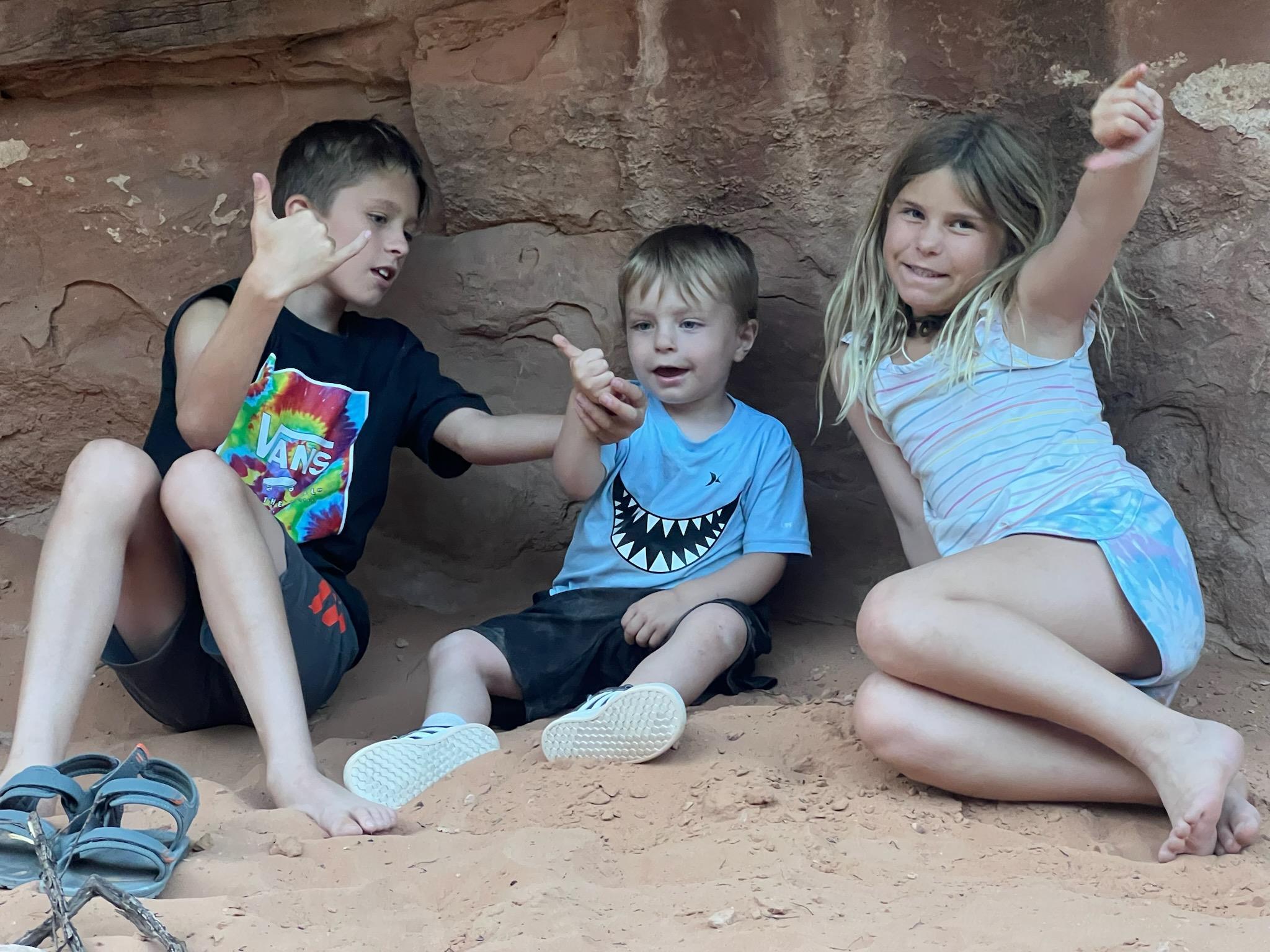 A group of kids sitting in the sand