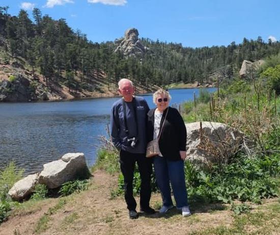 A man and woman standing next to a lake