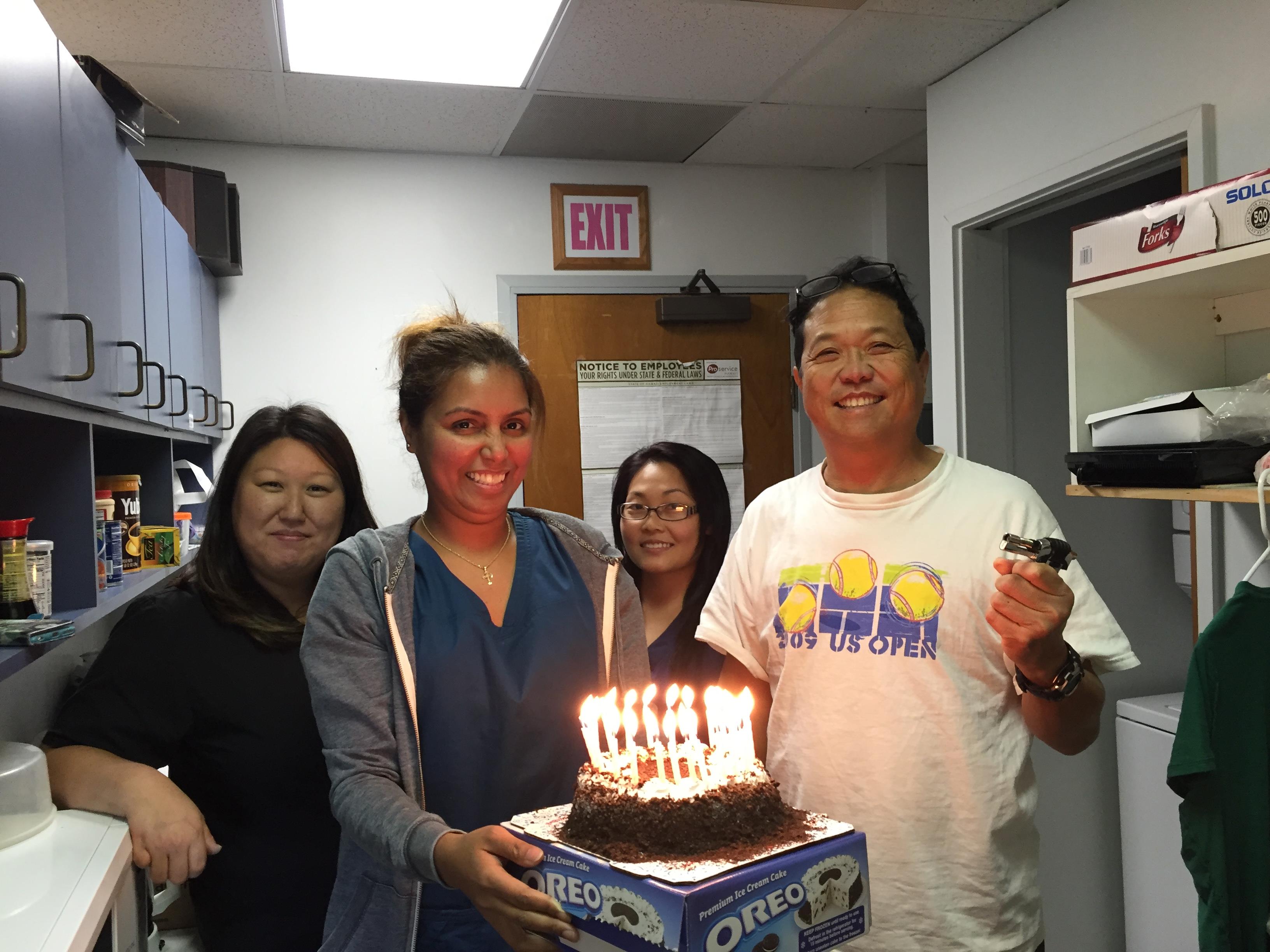 A group of people standing in a room with a cake