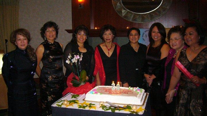 A group of women standing in front of a cake