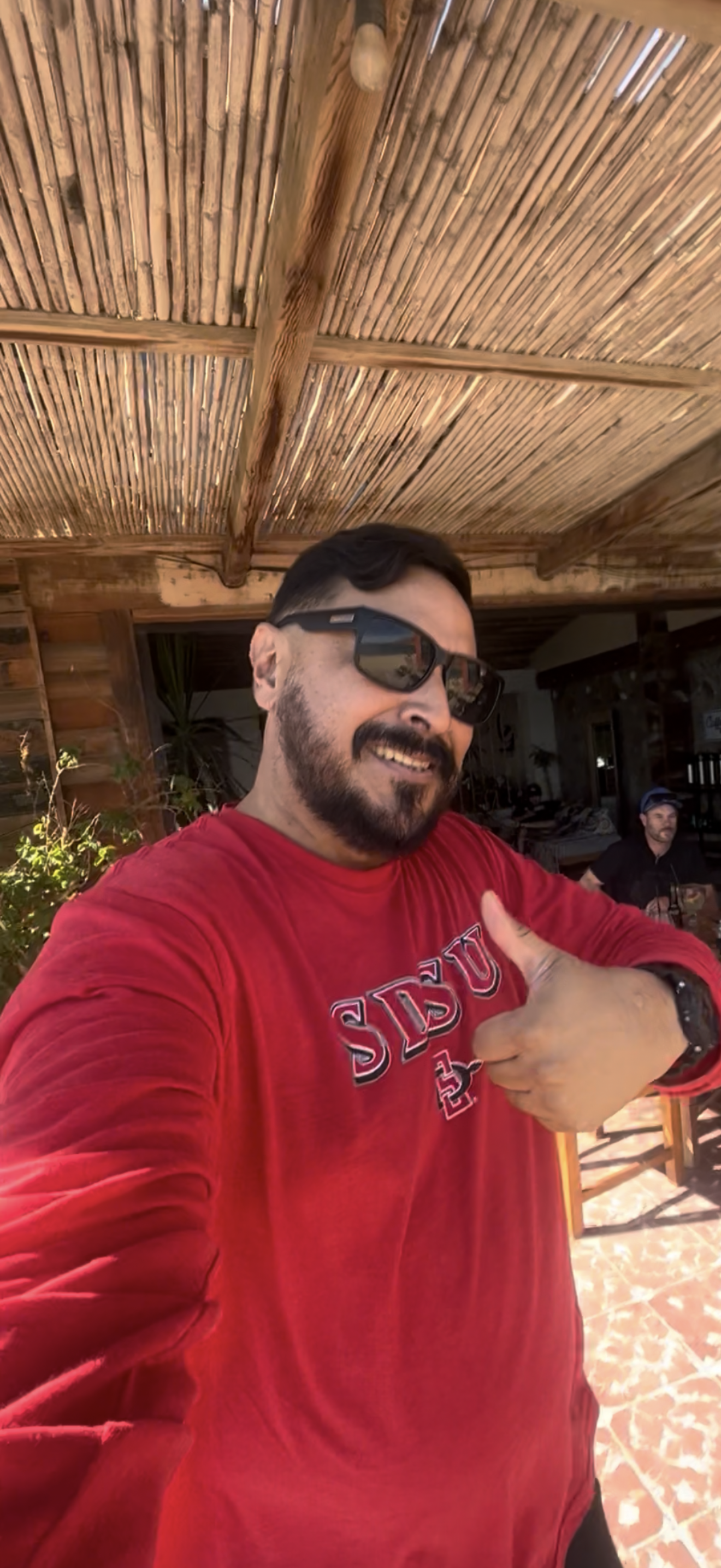 A man wearing sunglasses and giving a thumbs up