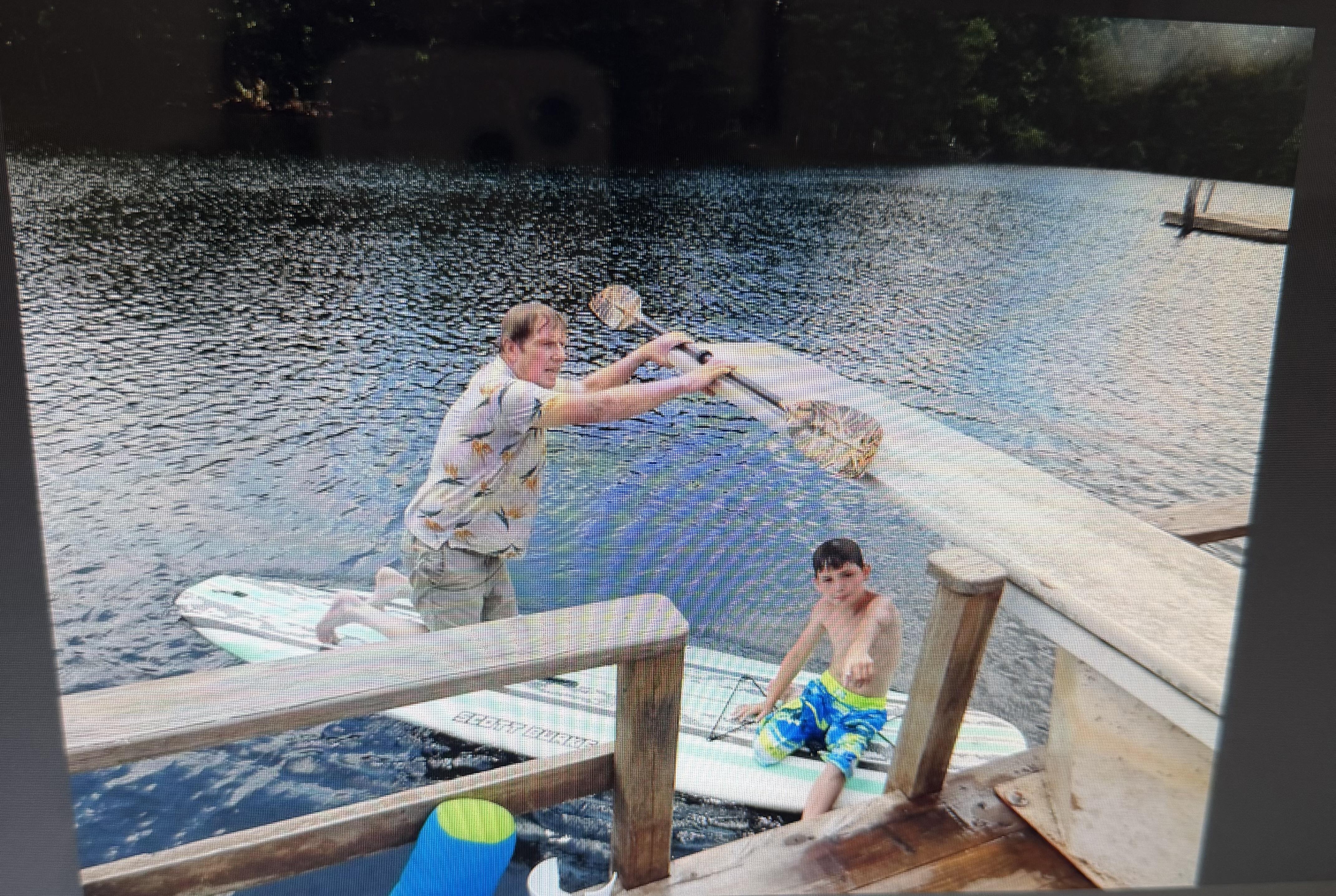 A man holding a paddle and a boy on a paddle board