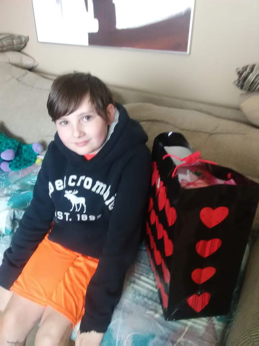 A boy sitting on a couch with a large bag