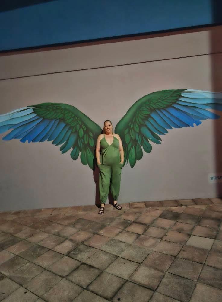 A woman standing in front of a wall with wings painted on it