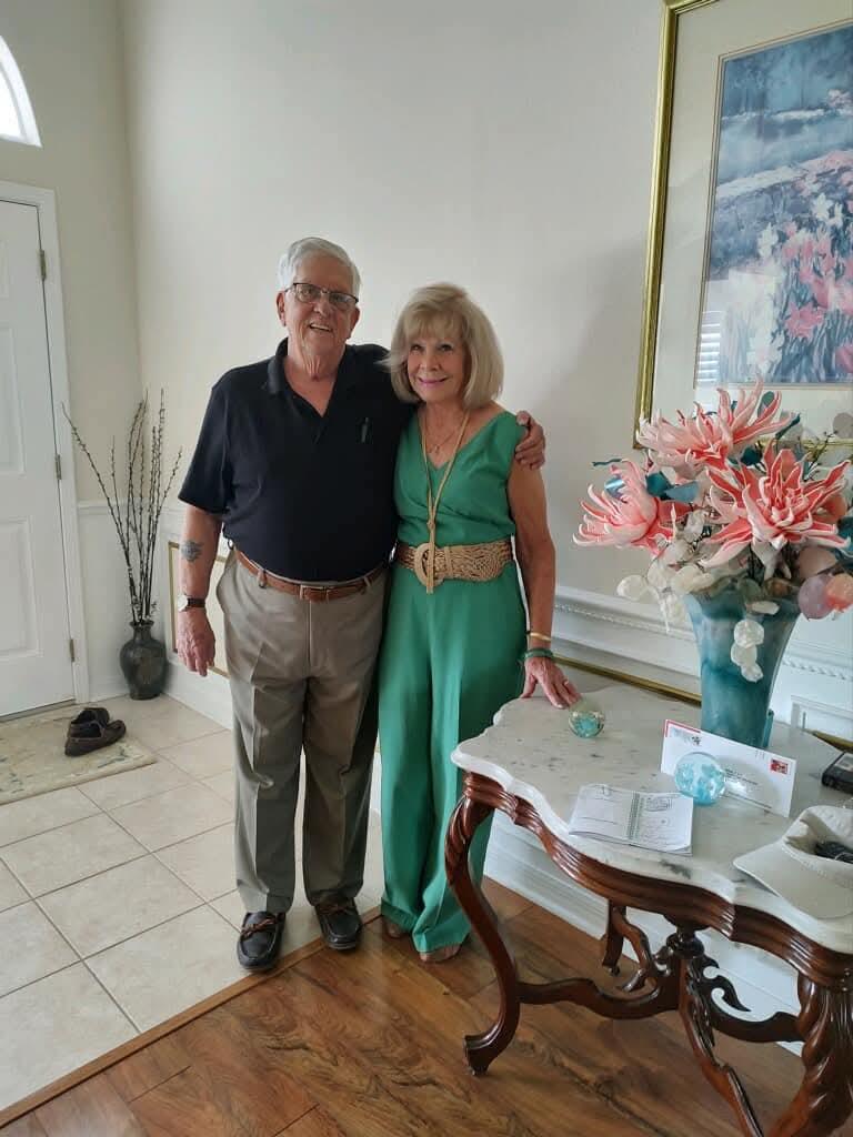 A man and woman standing next to a table