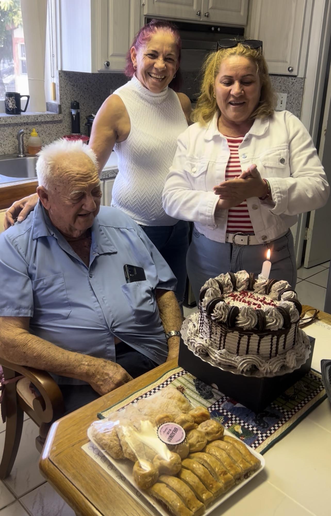 A group of people standing around a cake