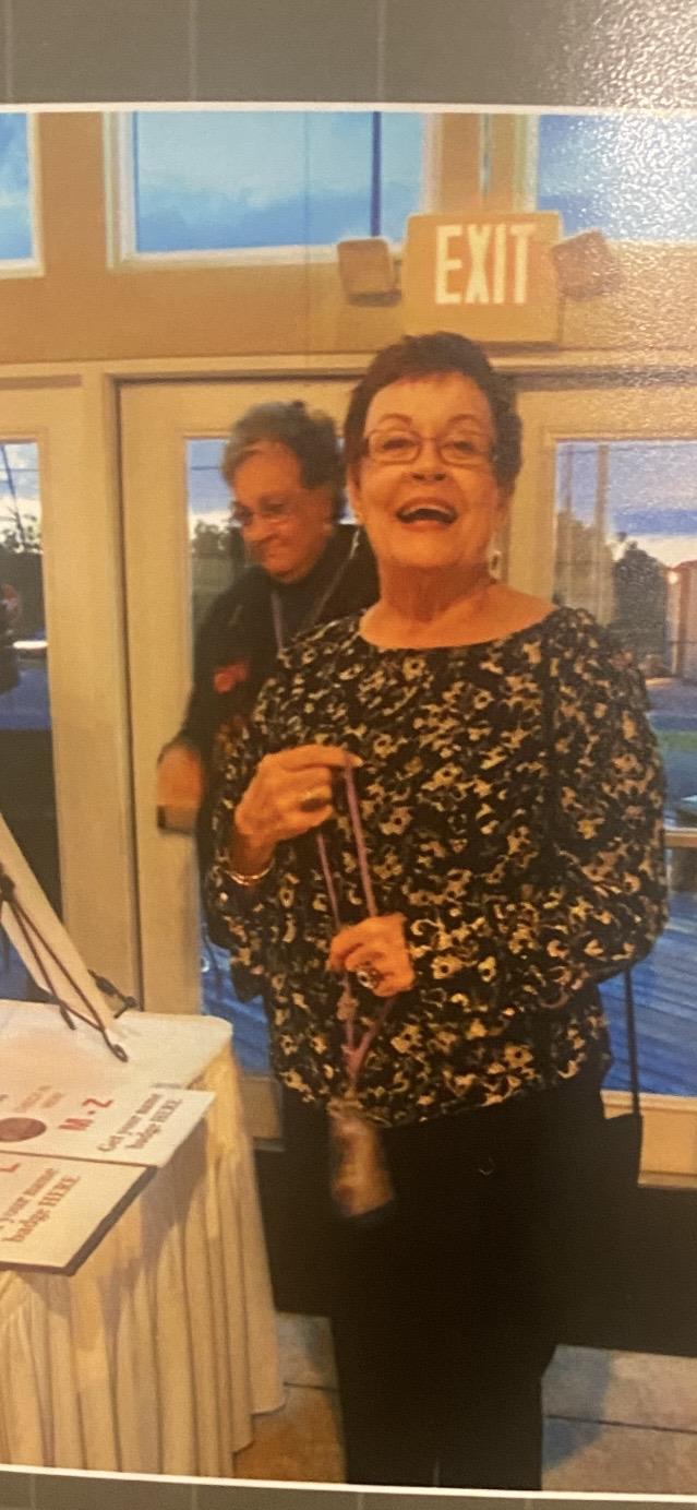 A woman smiling and holding a cane