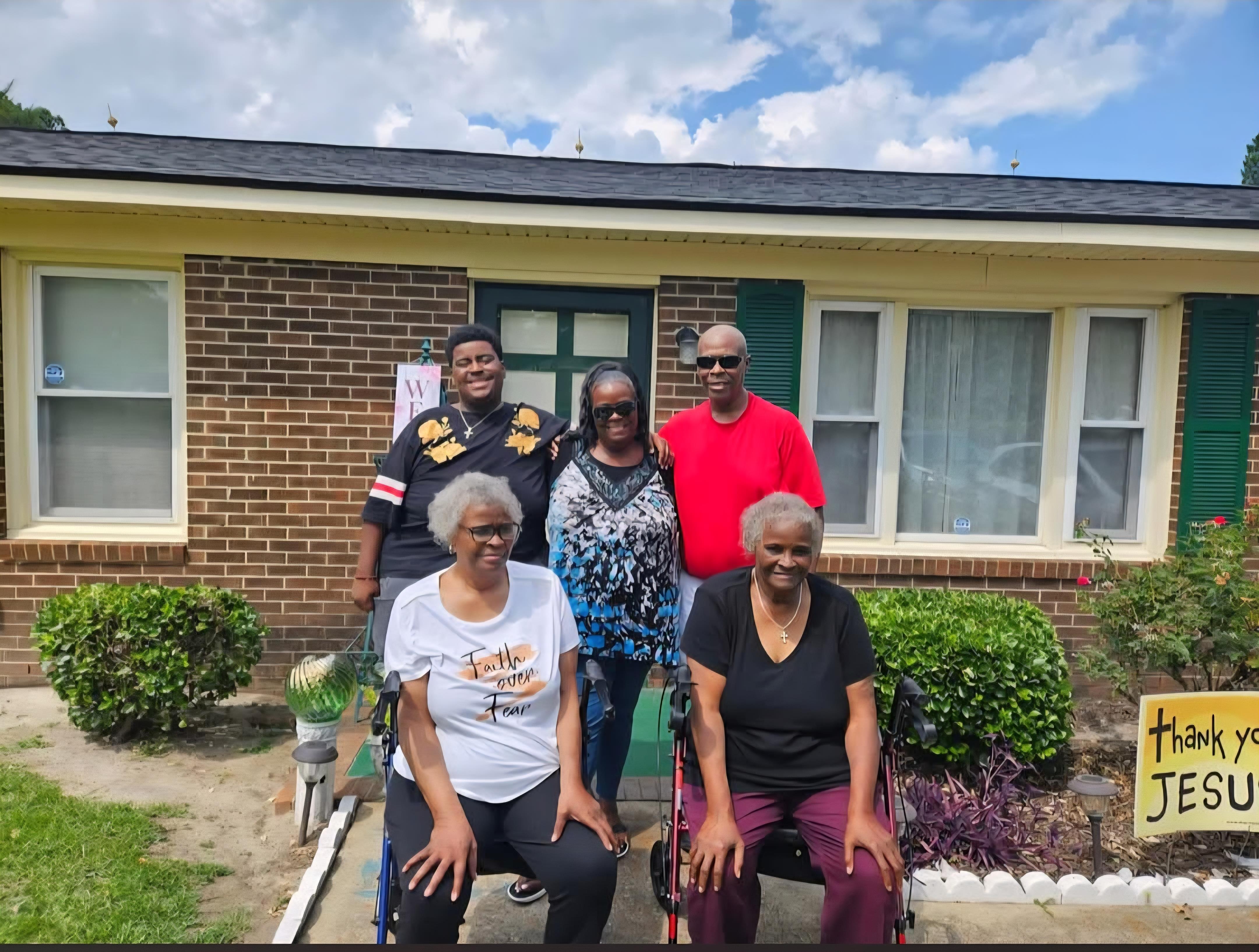 A group of people posing for a photo in front of a house