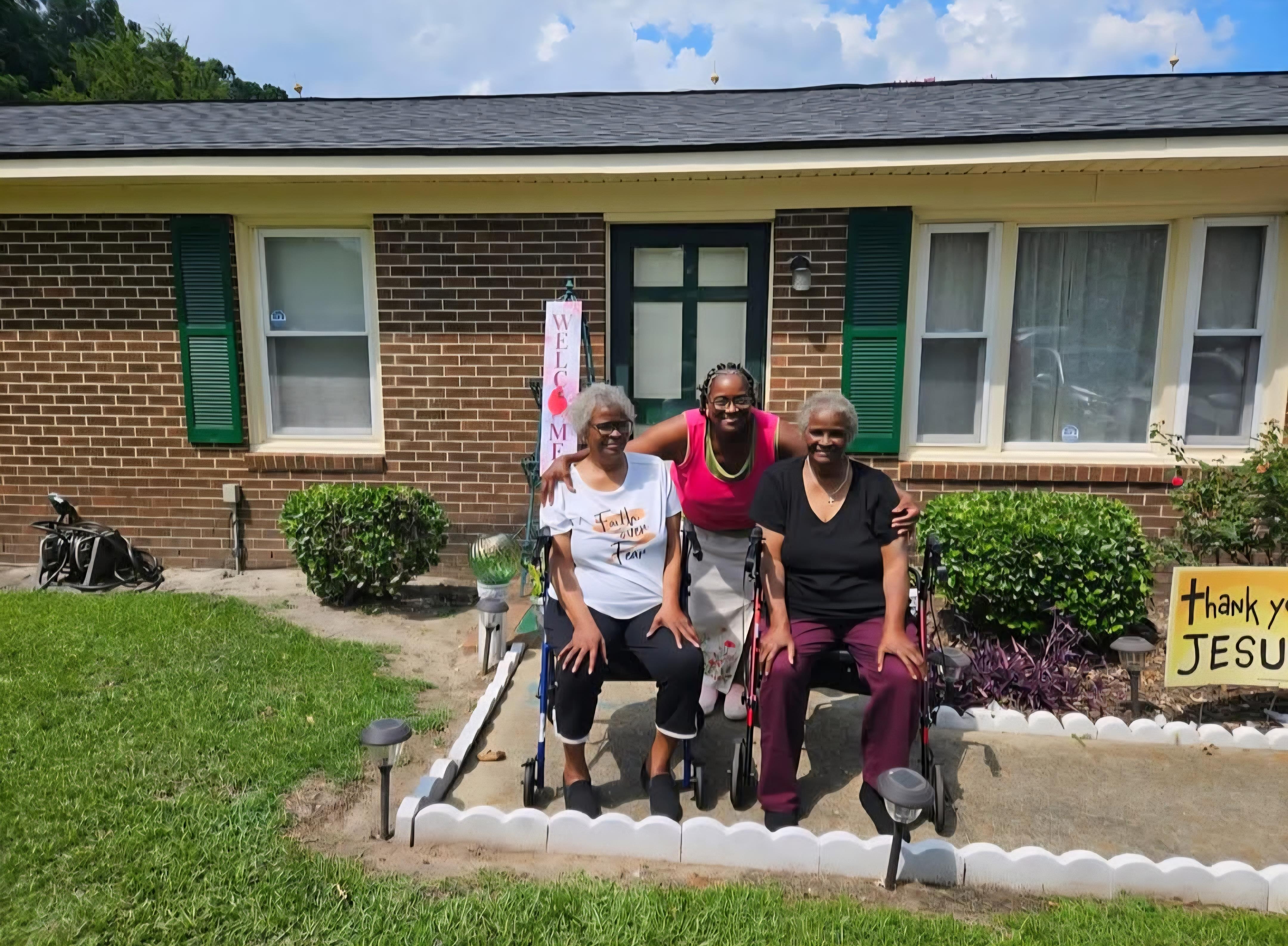 A group of women in wheelchairs in front of a house
