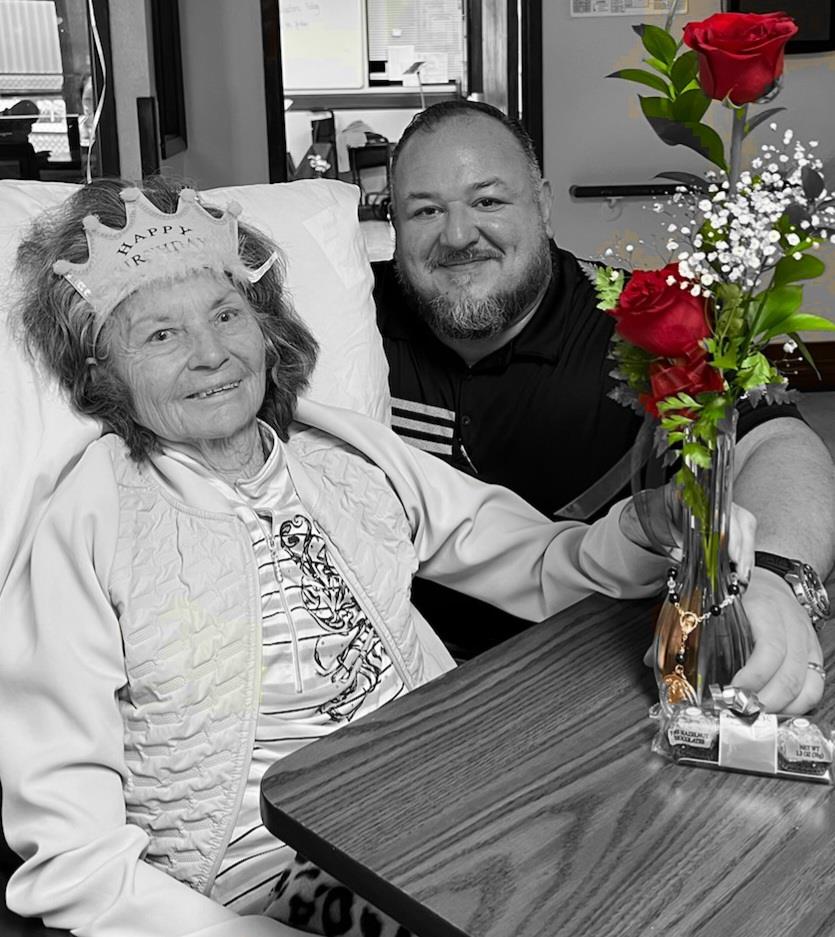 A man and woman sitting in a chair with a vase of flowers