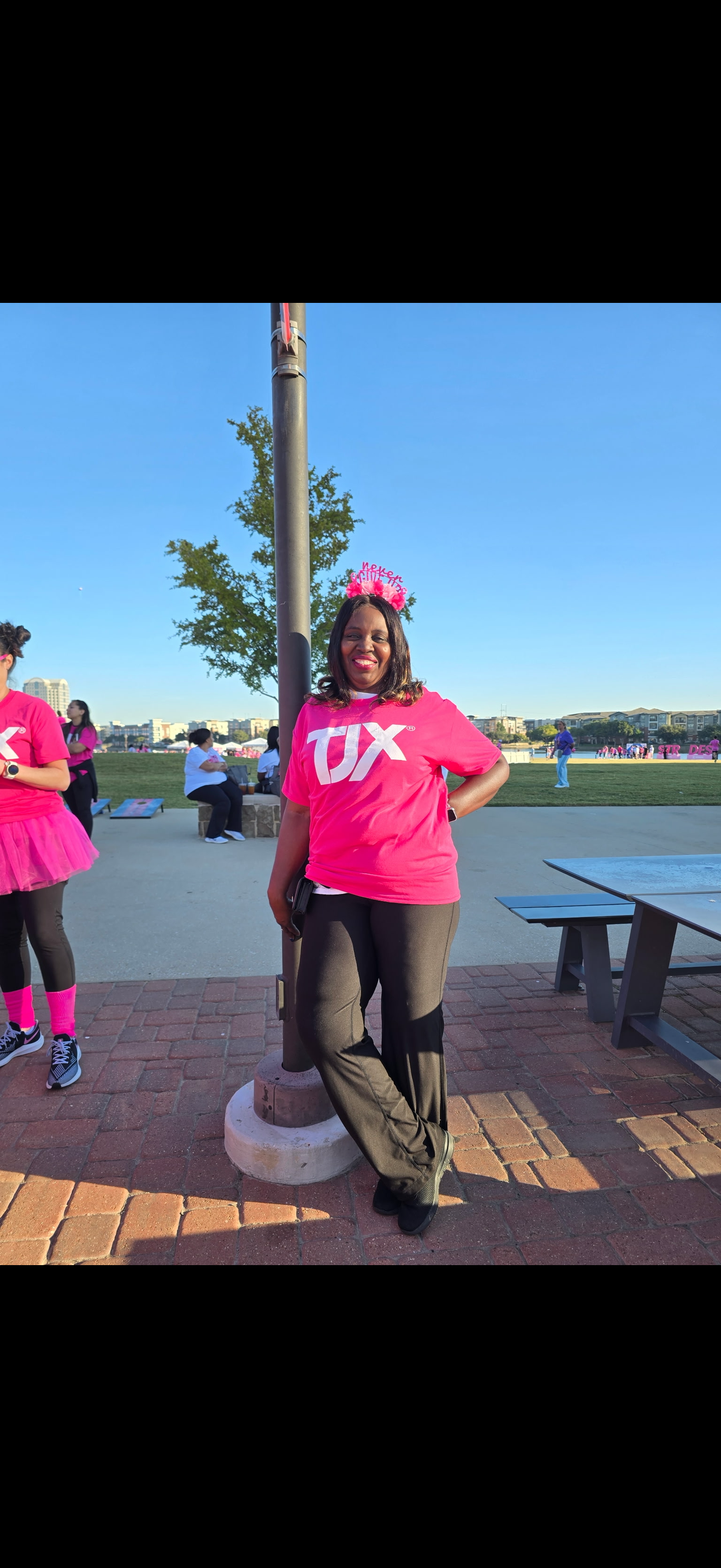 A woman in pink shirt and pink tutu standing next to a pole