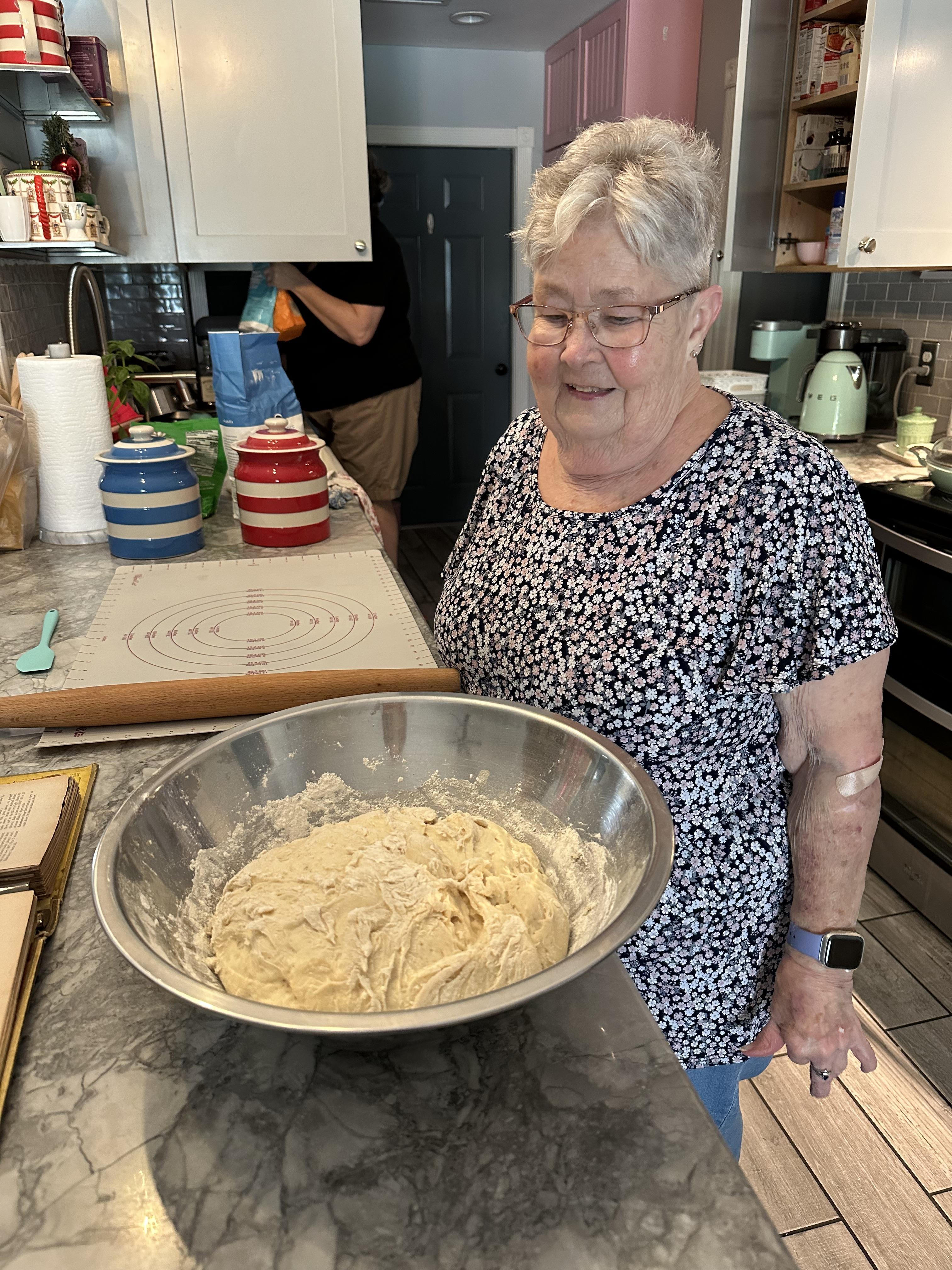 A woman standing in a kitchen with a bowl of dough