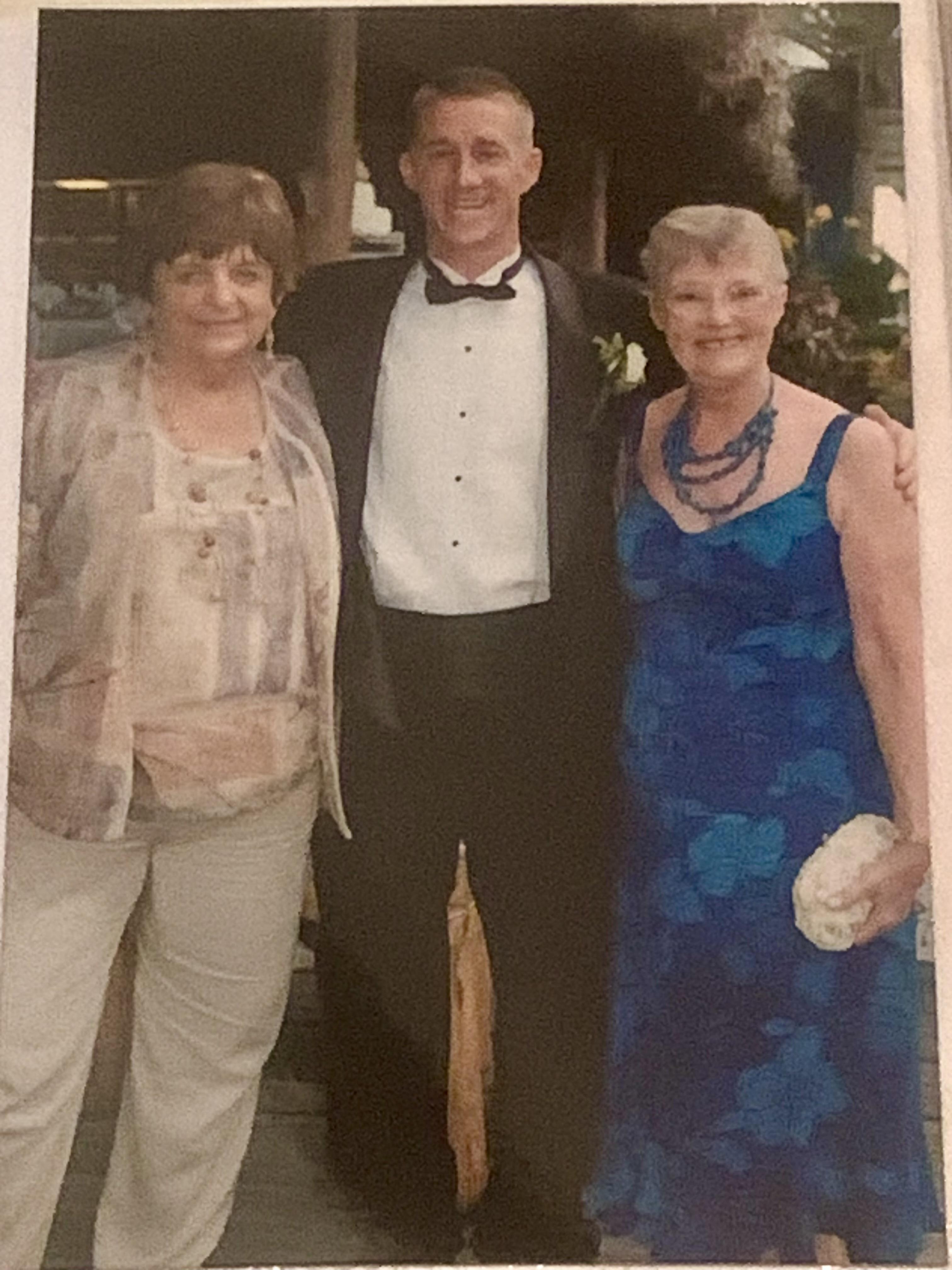 A man in a tuxedo with two women