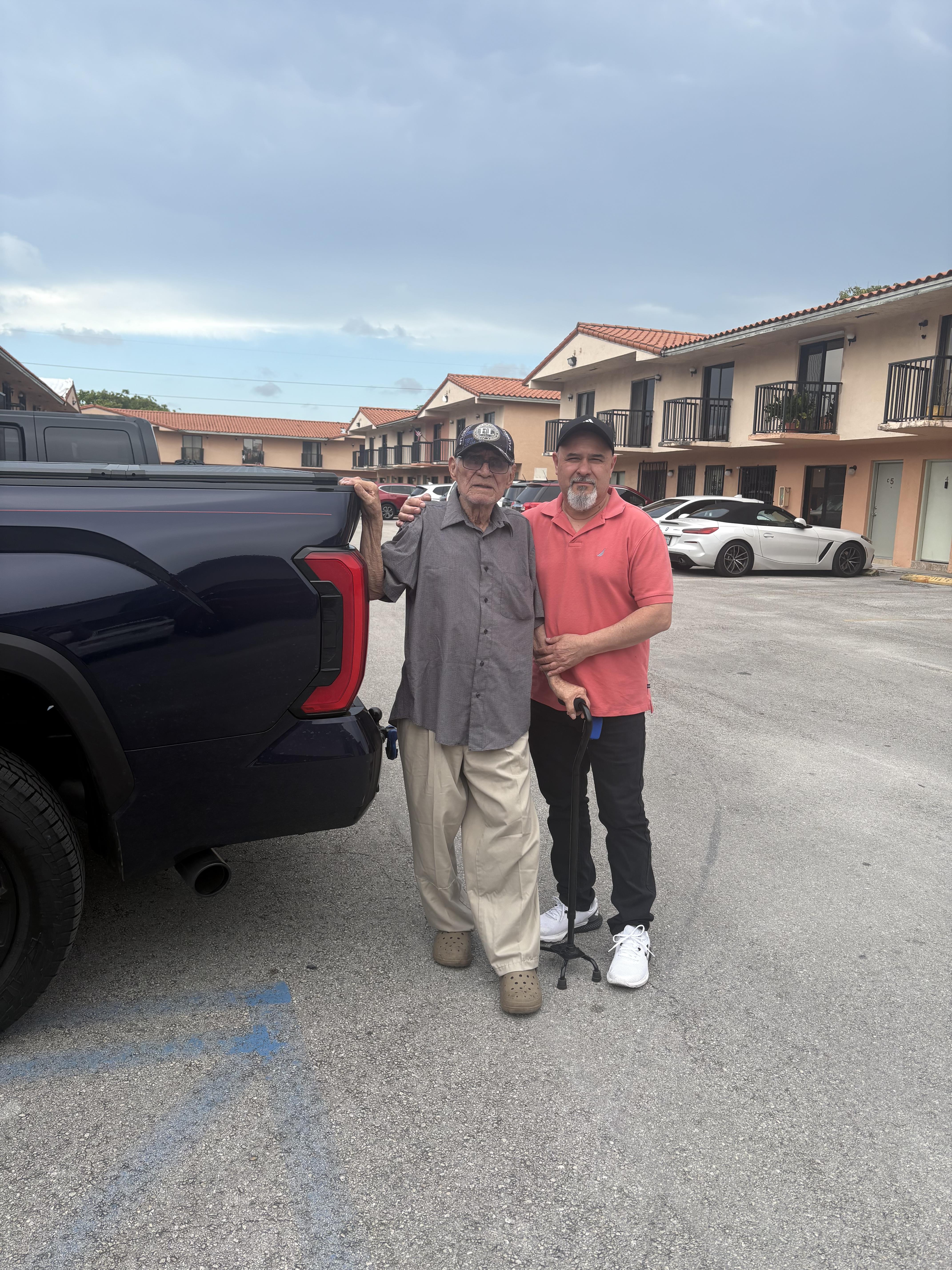 Two men standing next to a black truck