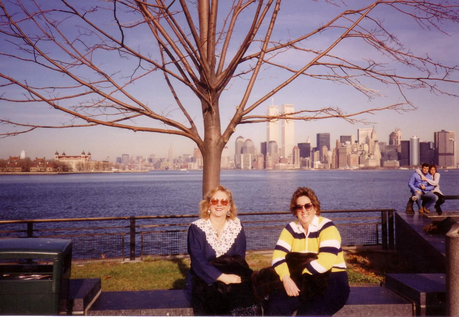 A couple of women sitting on a bench by a body of water