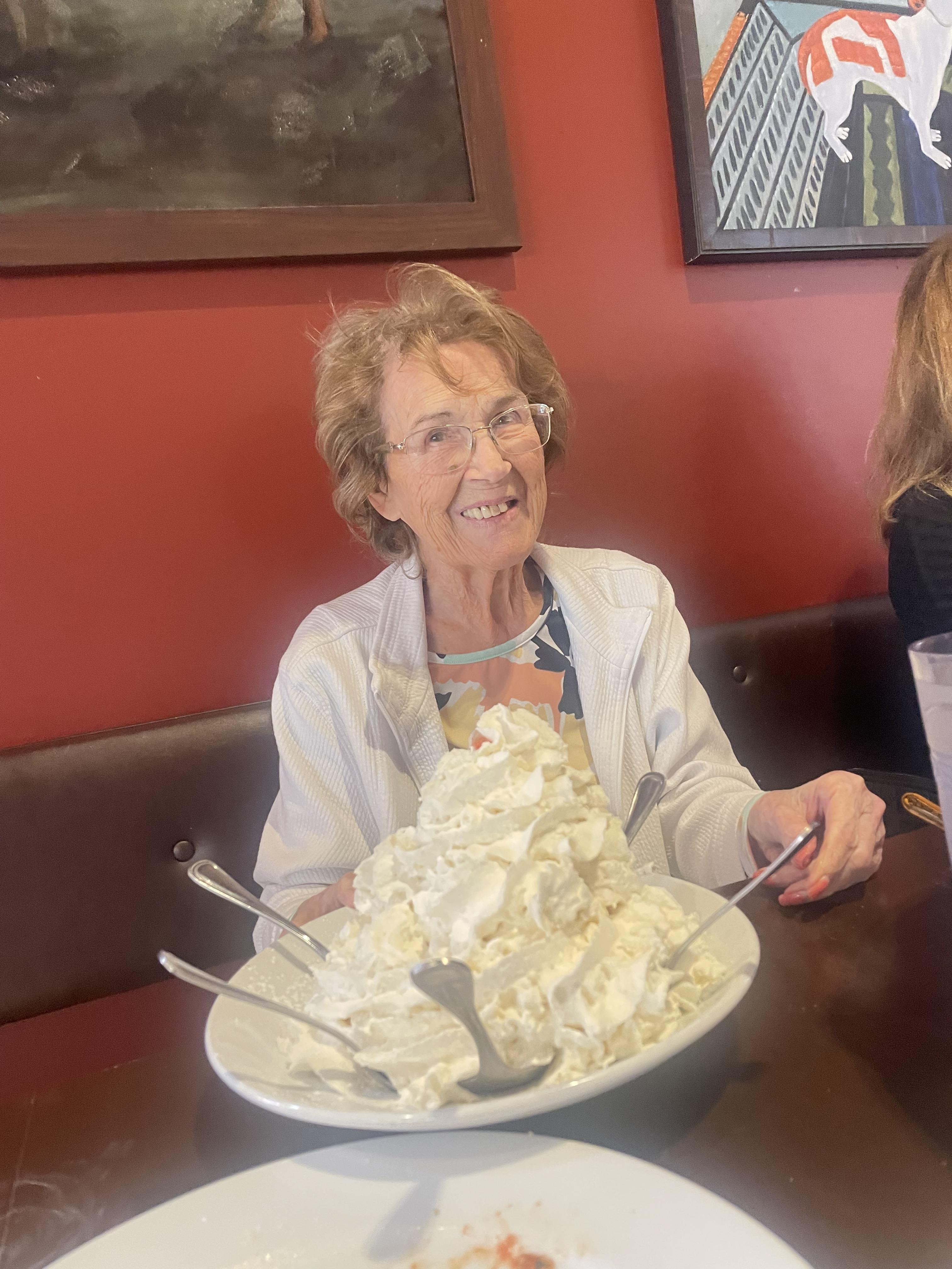 A woman sitting at a table with a plate of whipped cream