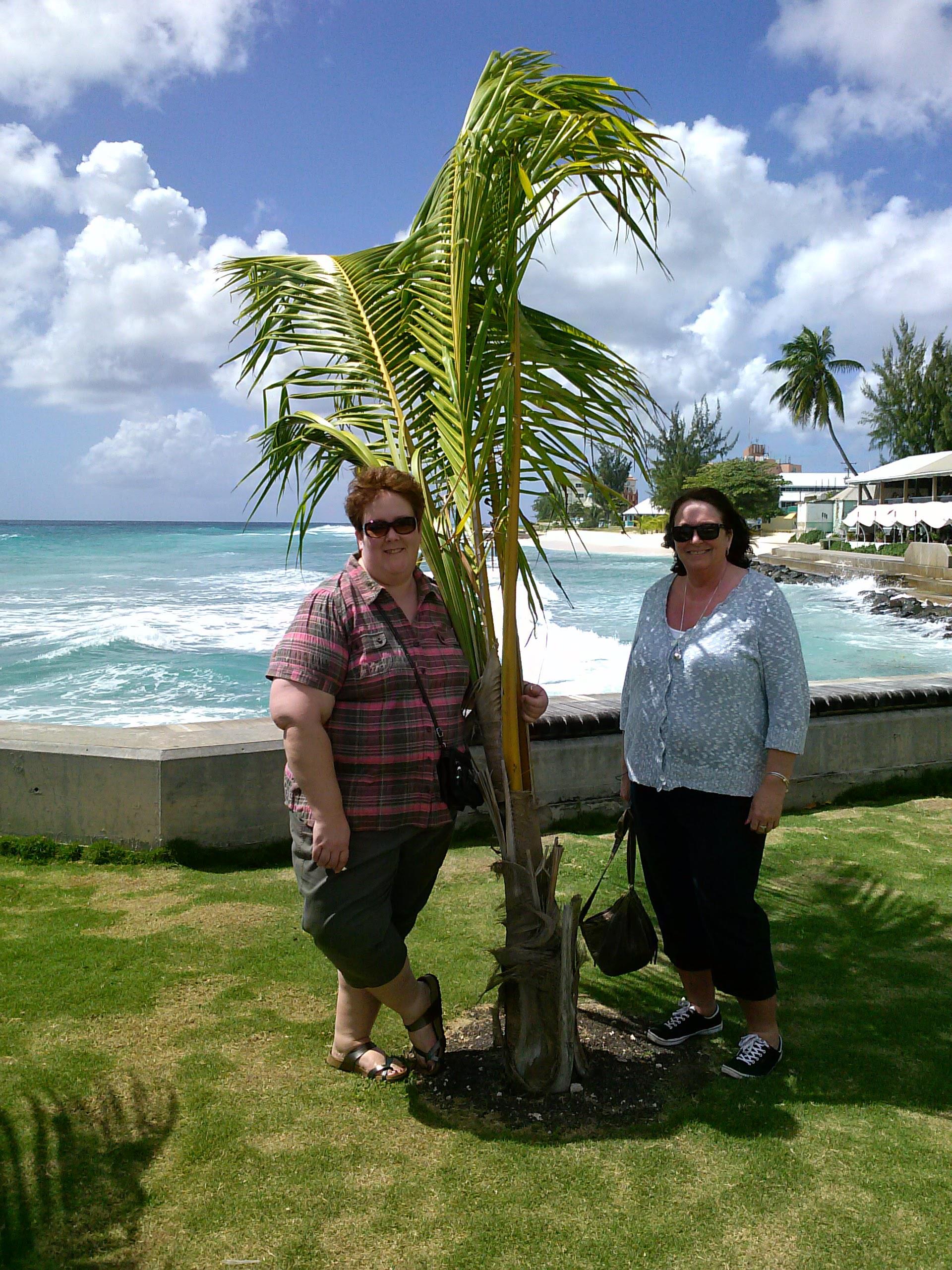 Two women standing next to a palm tree