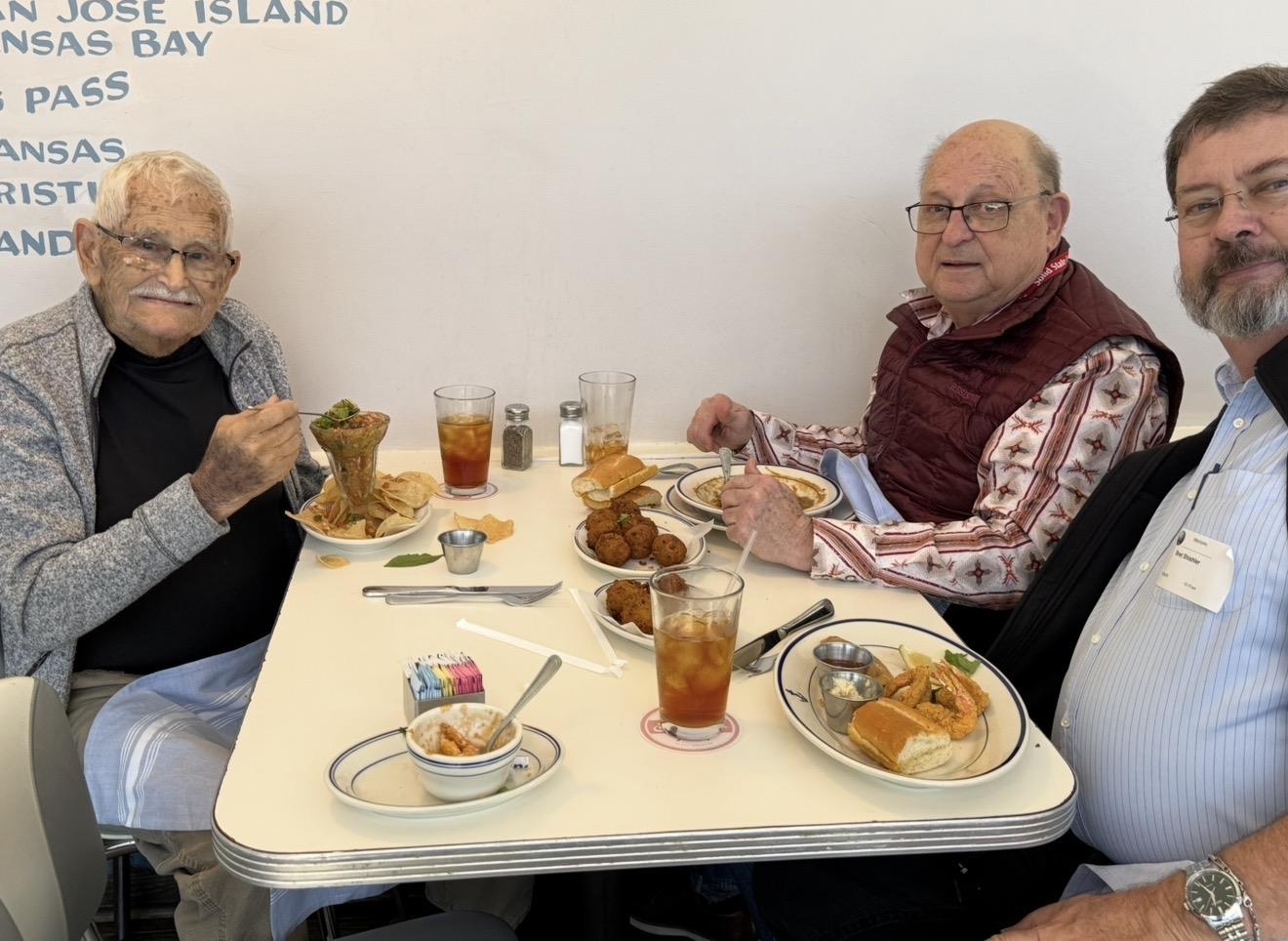 Two men sitting at a table eating food