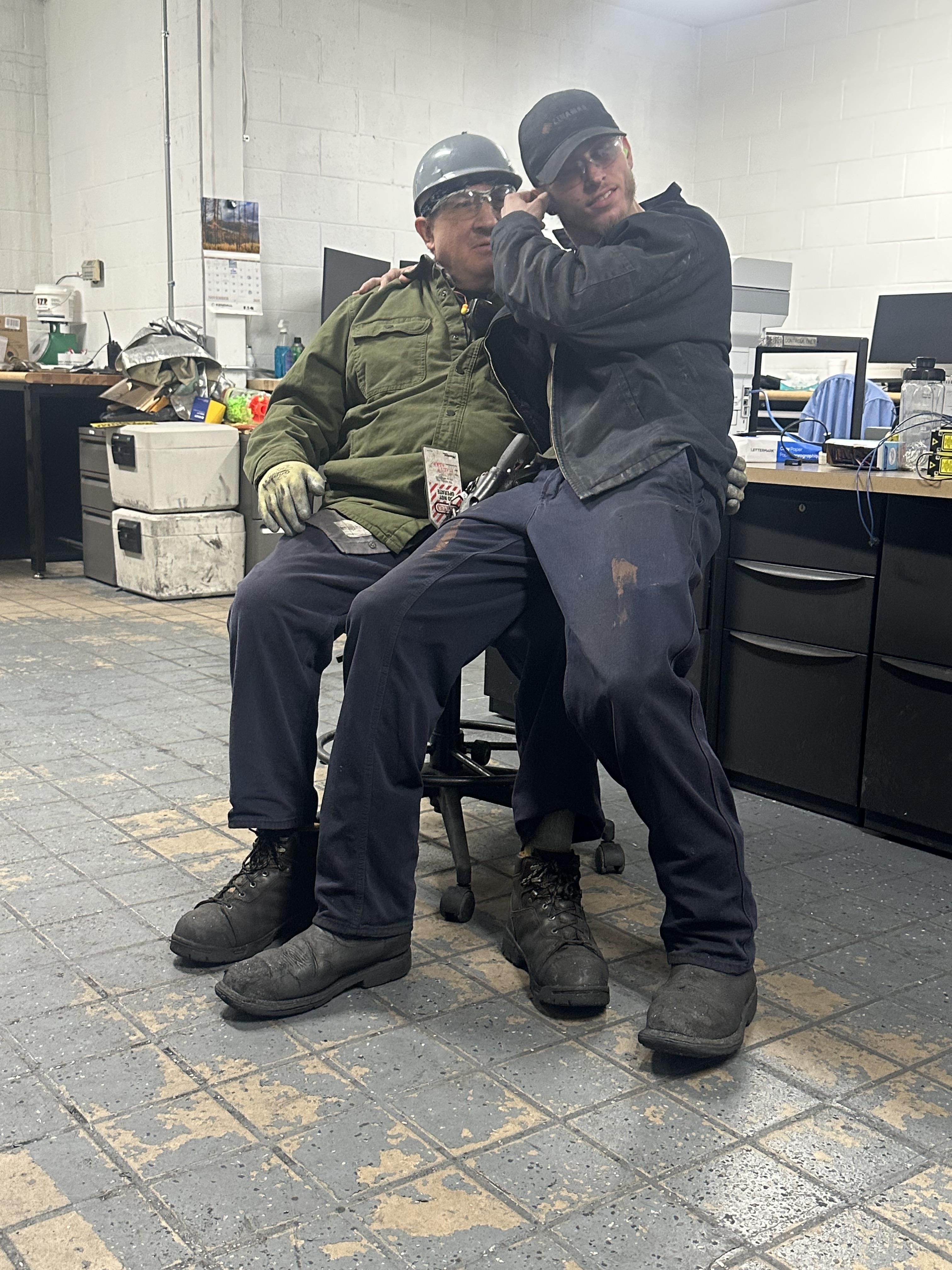Two men sitting on a chair in a room