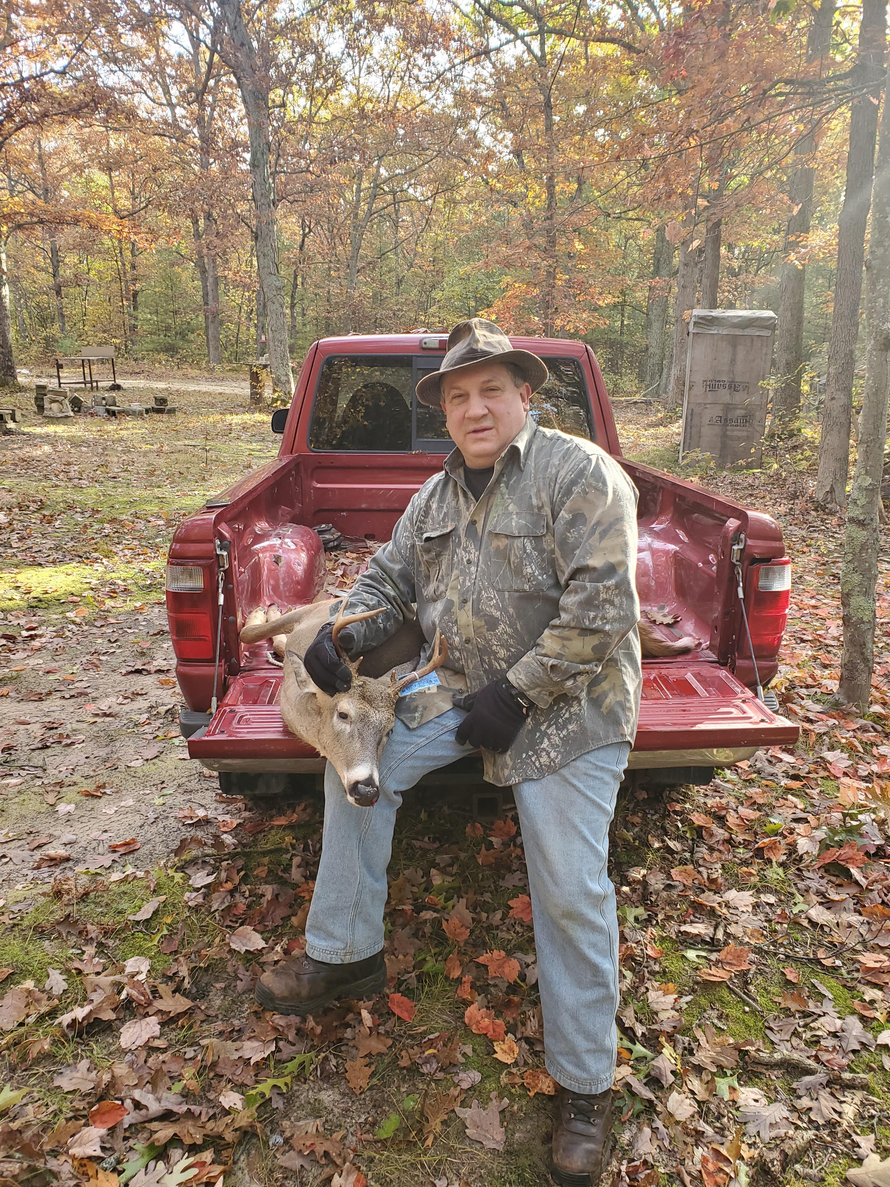 A man holding a deer in the back of a truck