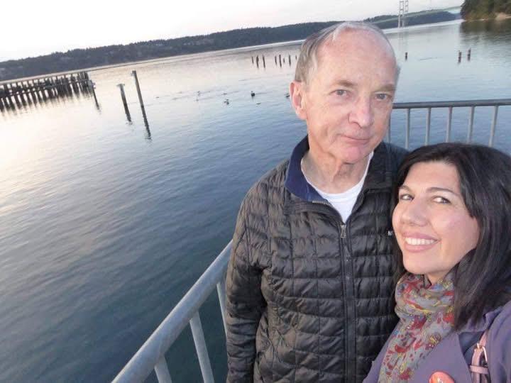 A man and woman standing on a railing next to water