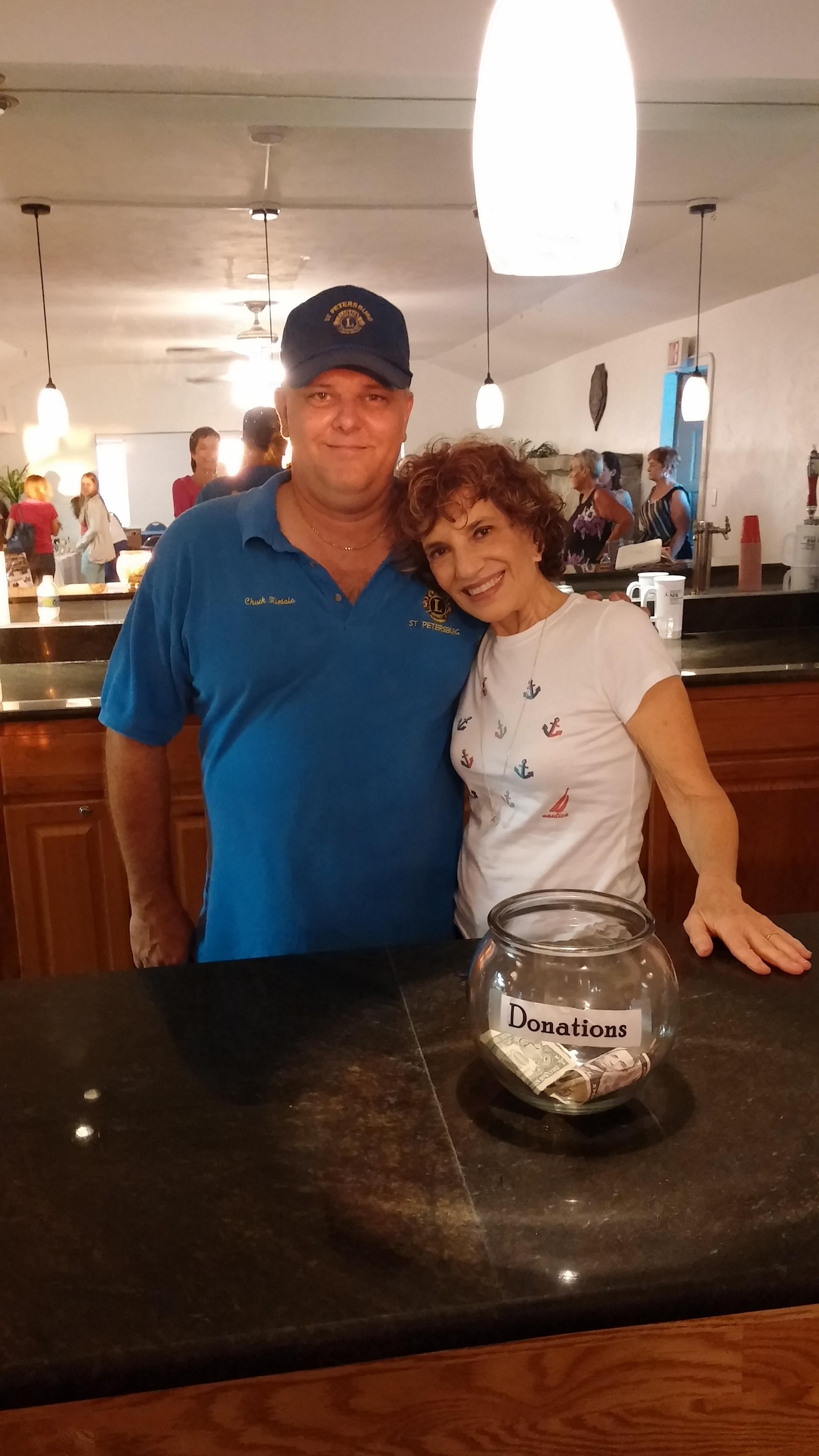A man and woman standing next to a glass jar of donations