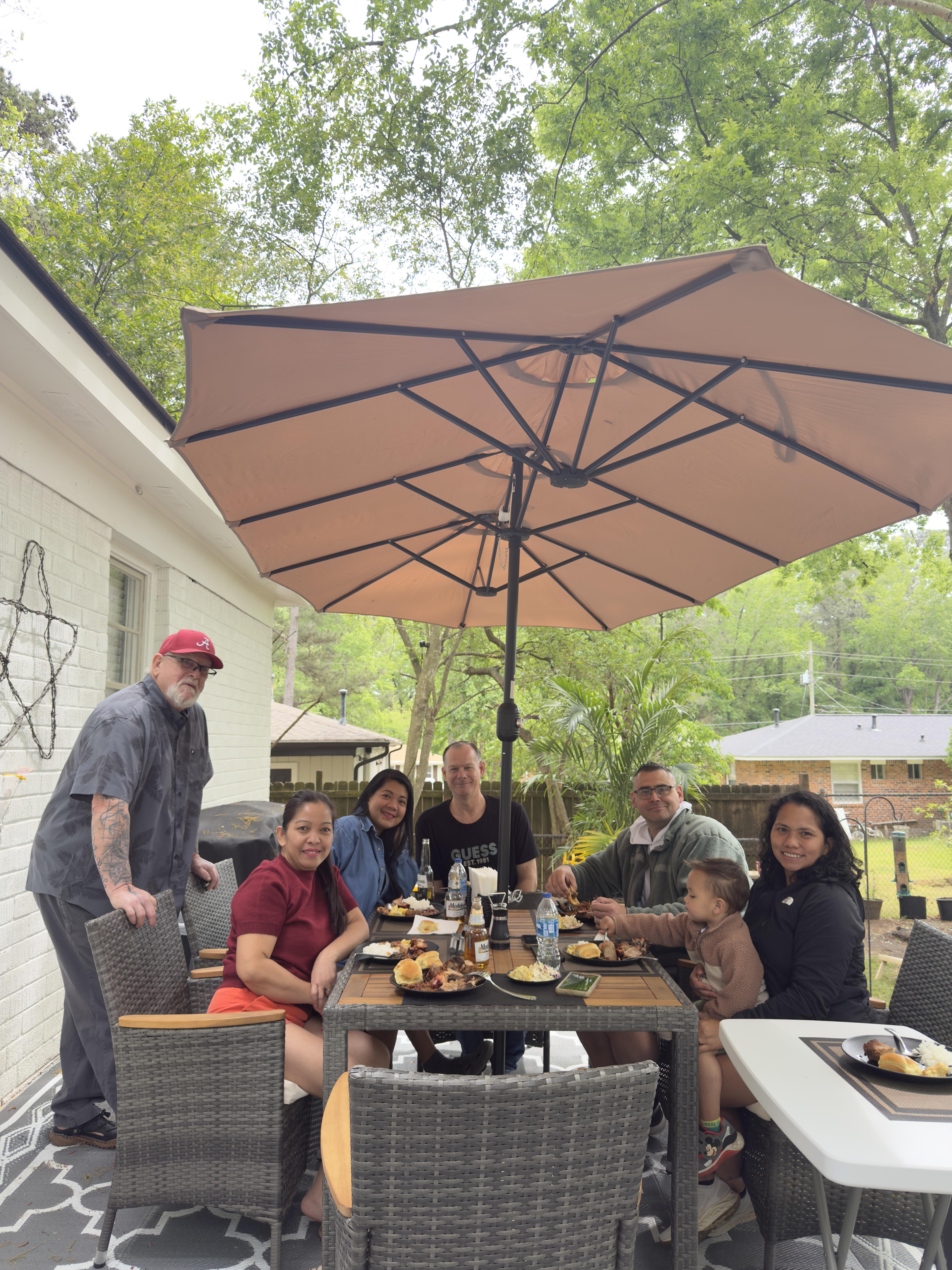 A group of people sitting at a table under an umbrella