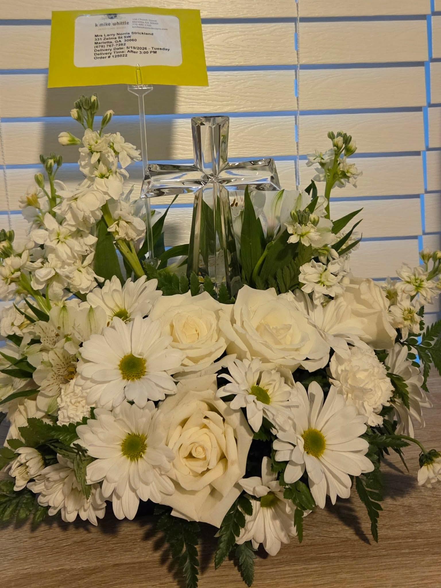 A bouquet of white flowers with a cross and a yellow card