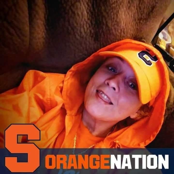 A woman in an orange hoodie and hat