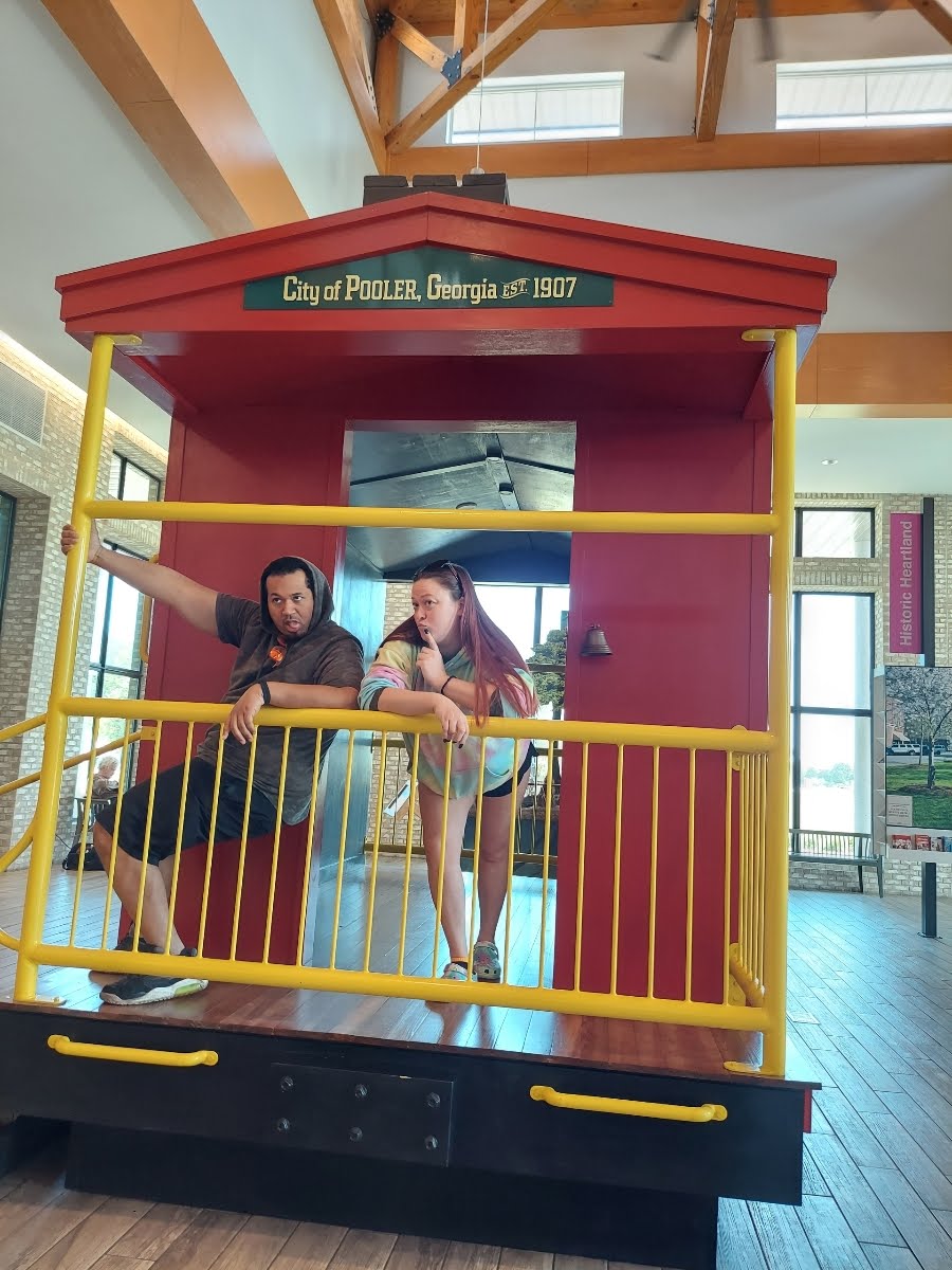 A man and woman posing for a picture in a small yellow and red structure