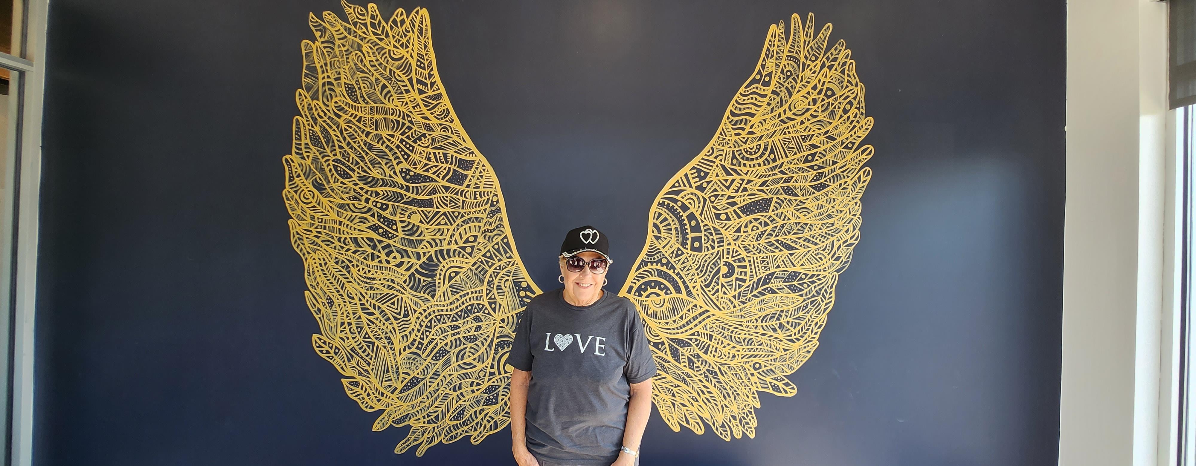 A man standing in front of a wall with wings