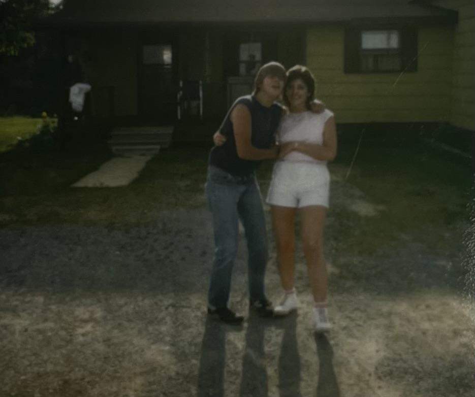A couple of people hugging in front of a house