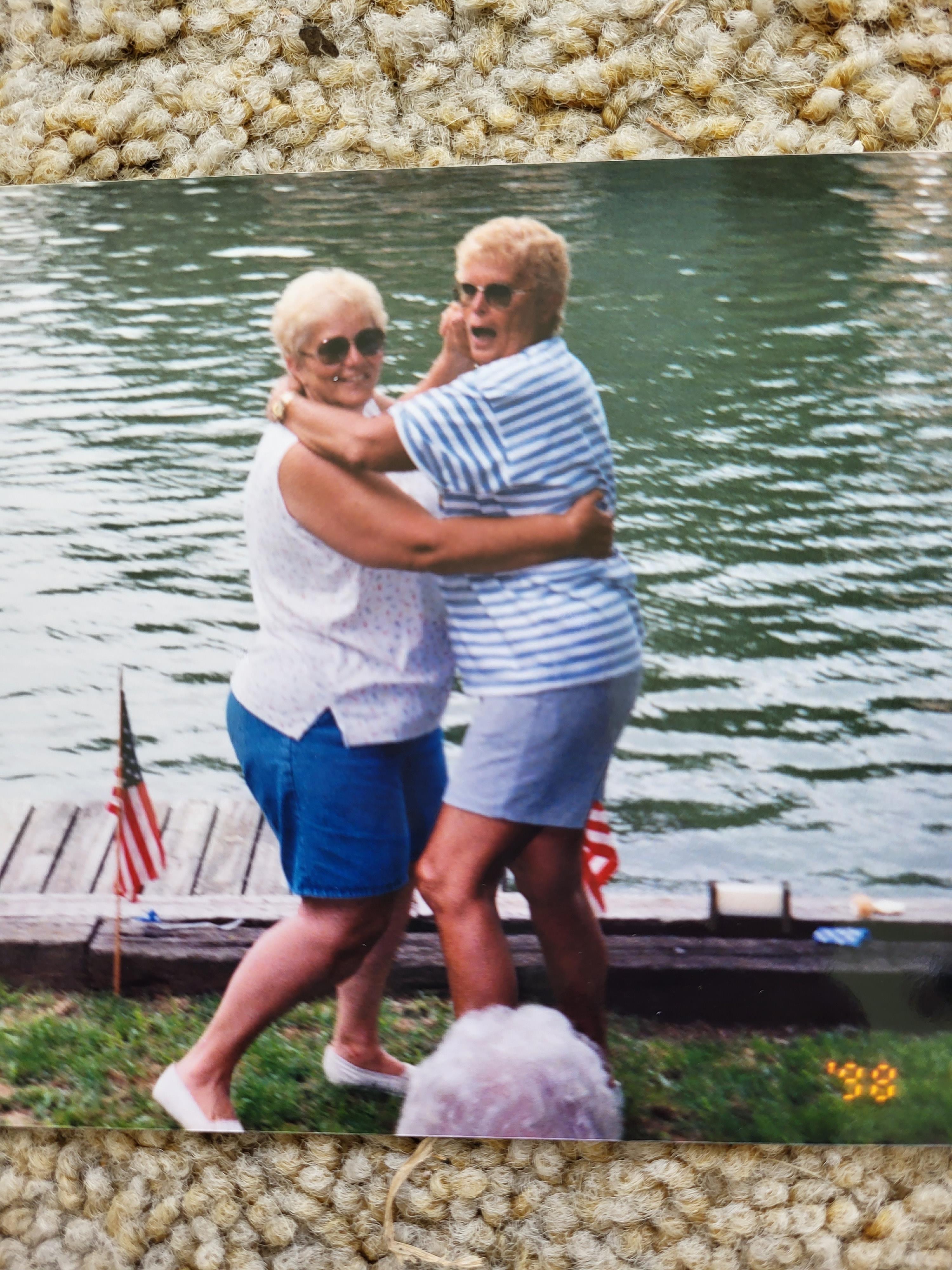Two women hugging each other by a lake