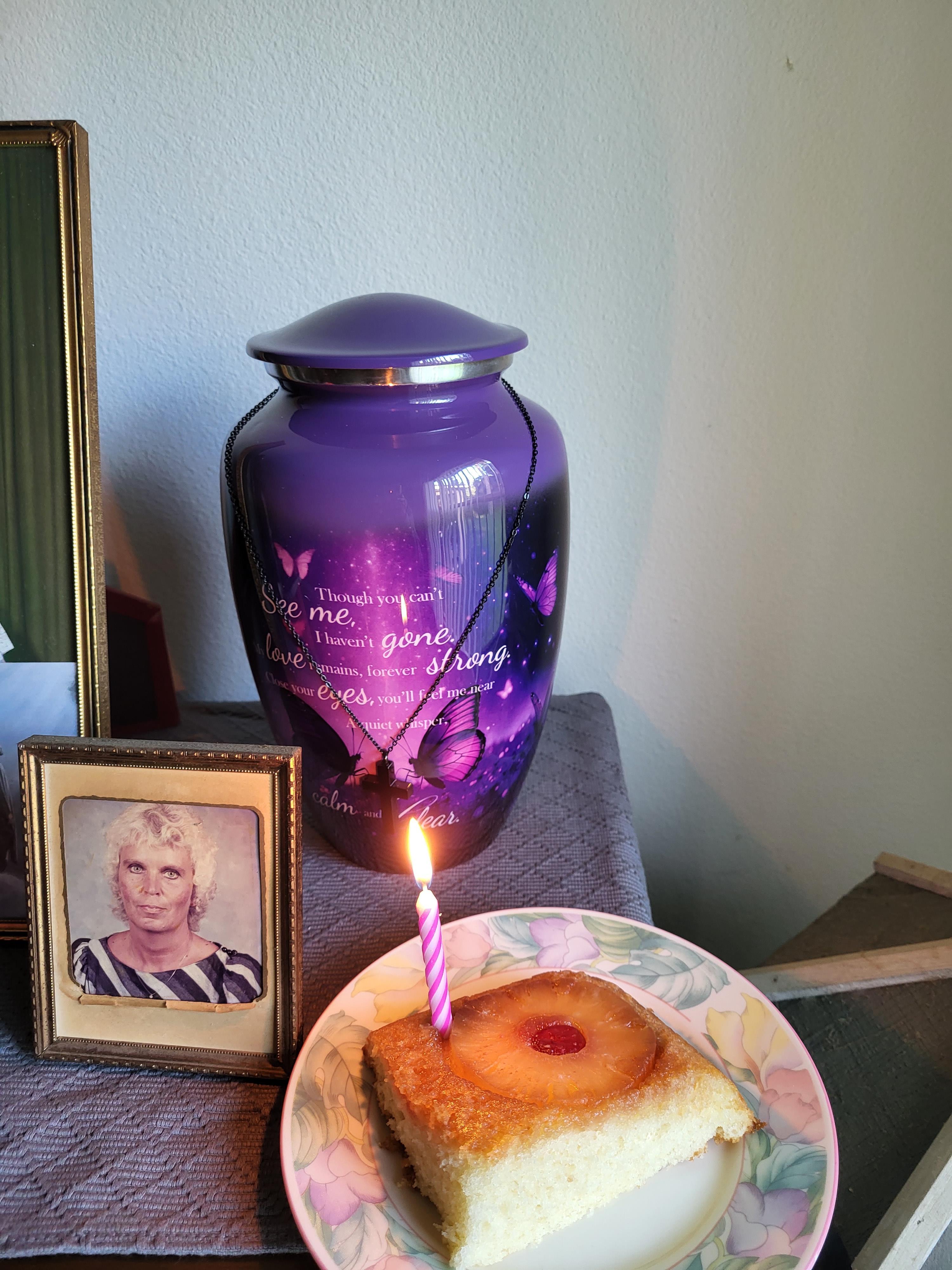 A purple urn with a piece of cake and a lit candle