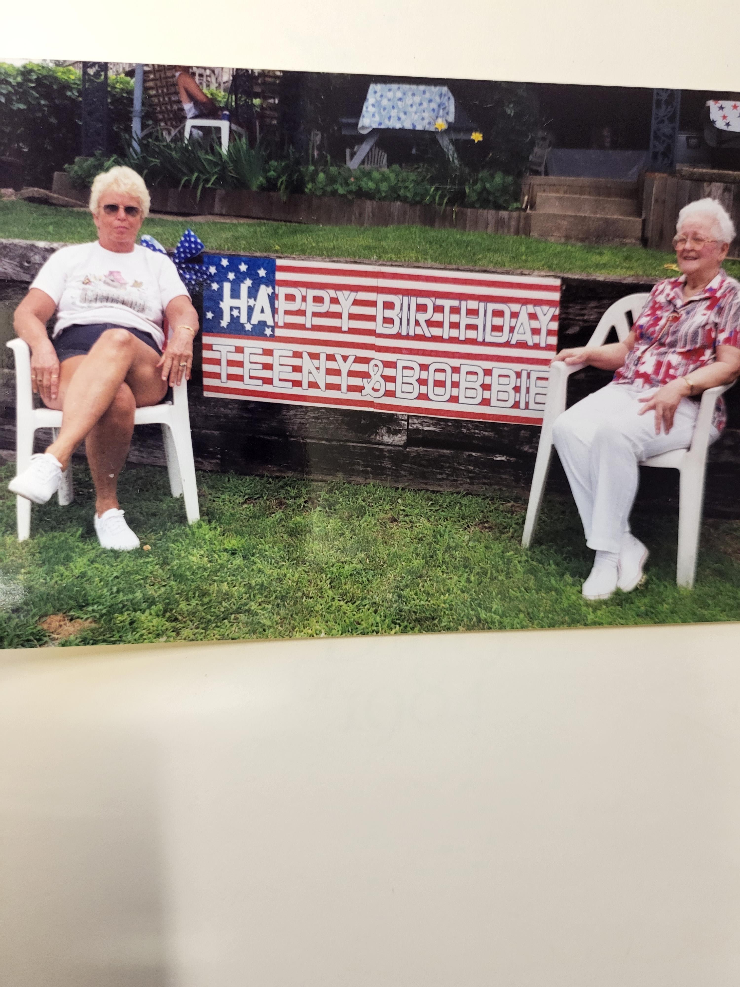 Two women sitting in chairs in a yard