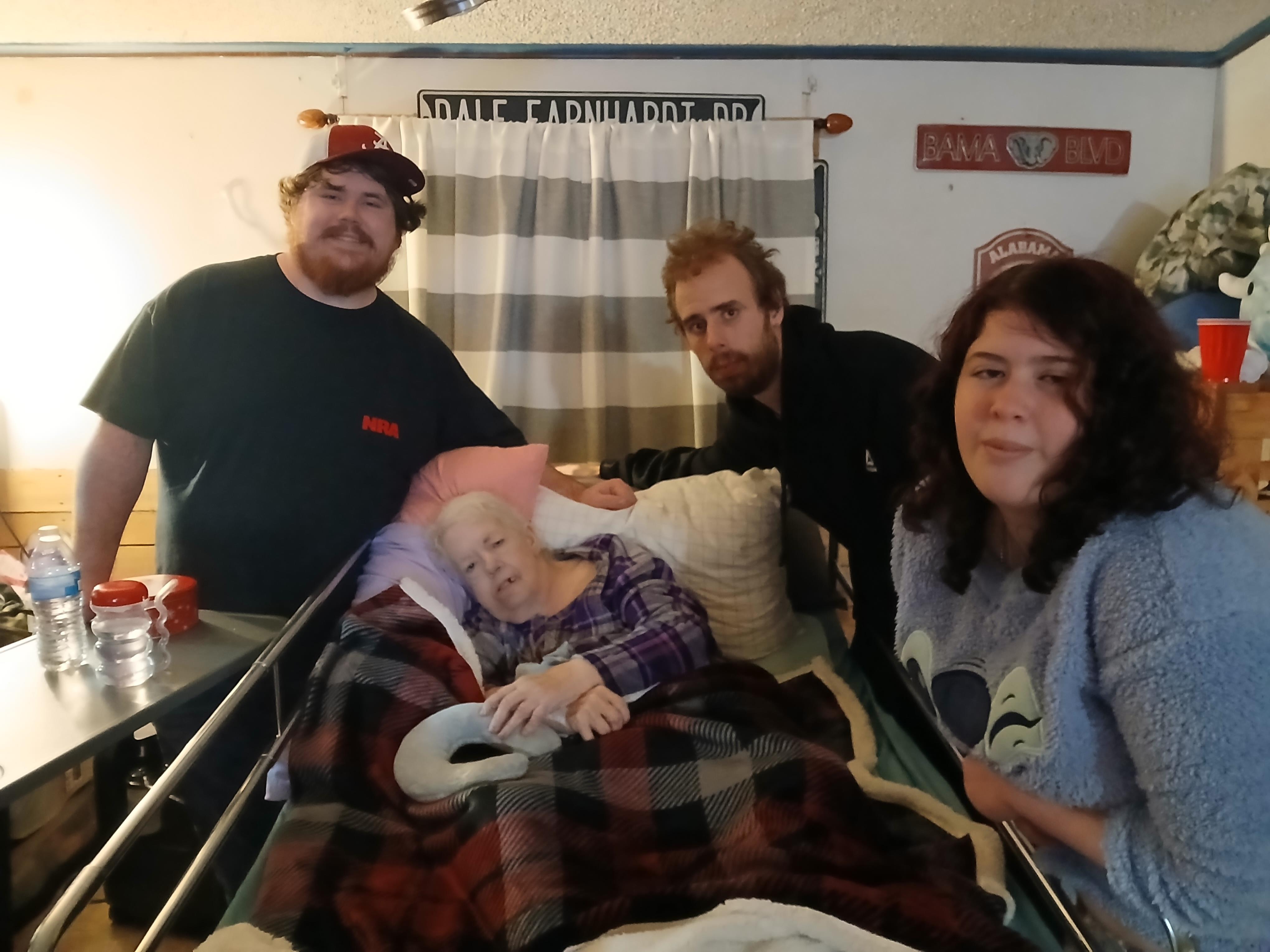 A group of people standing around a woman in a bed