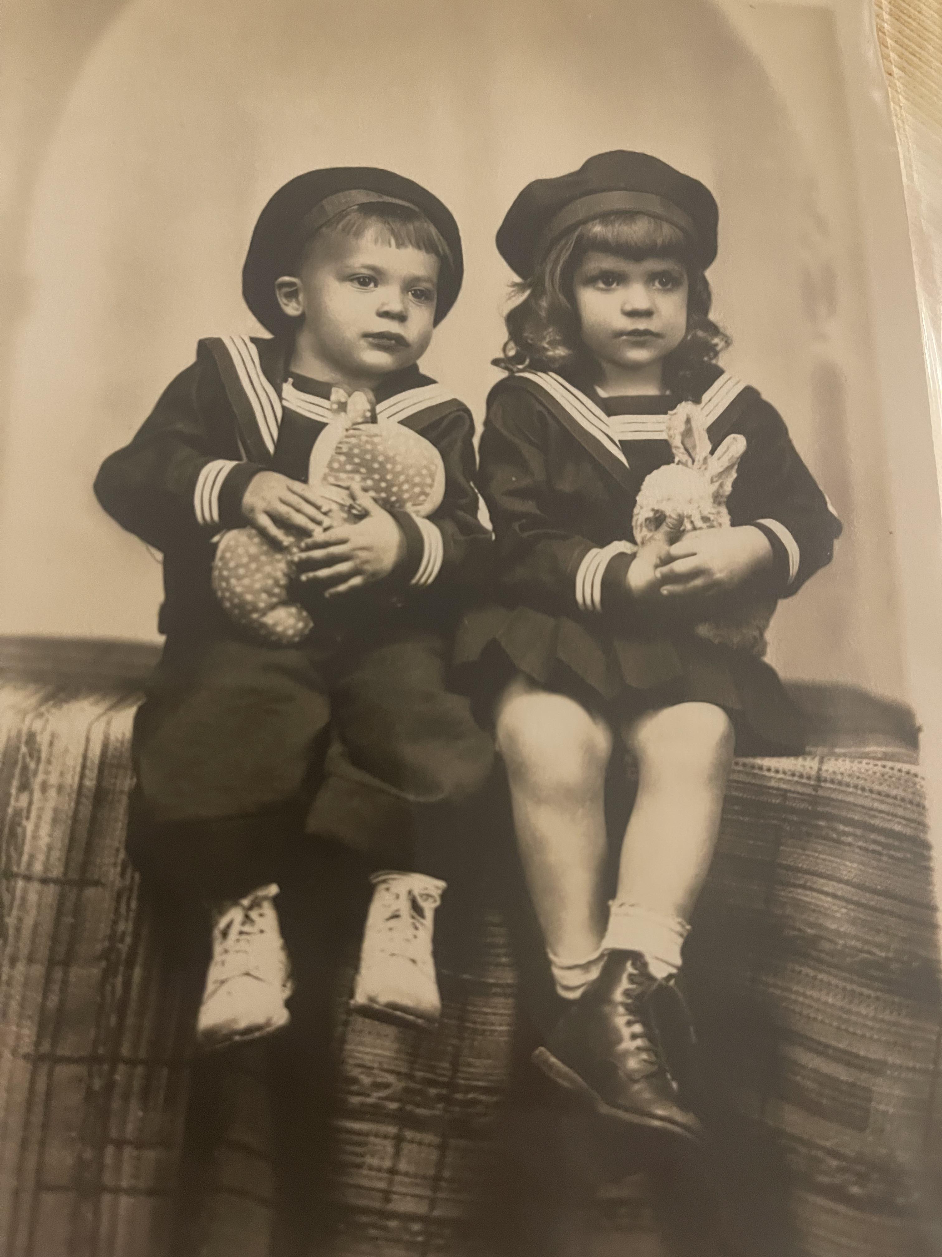 A boy and girl sitting on a bench holding toys