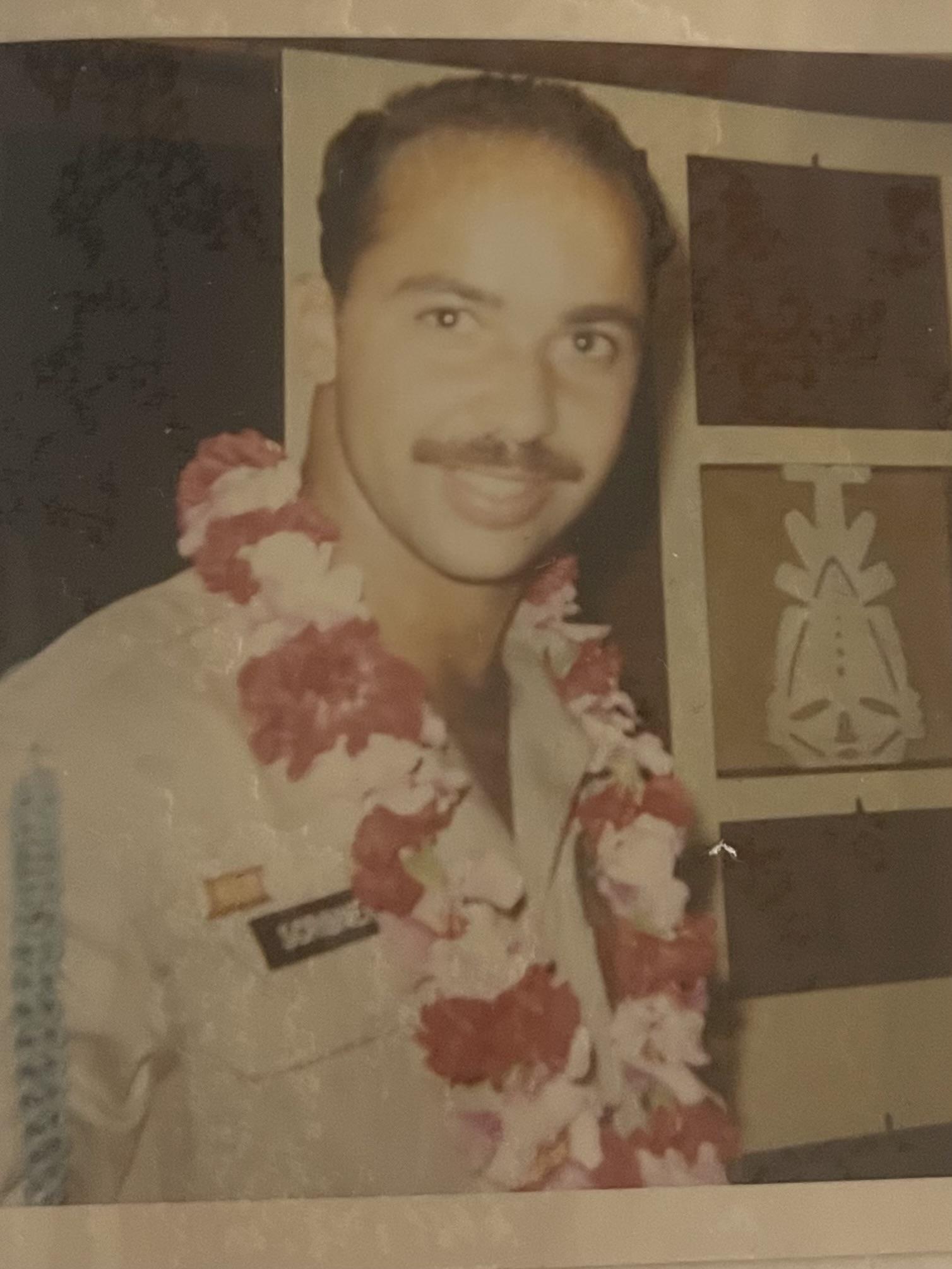 A man with a mustache wearing a flower lei