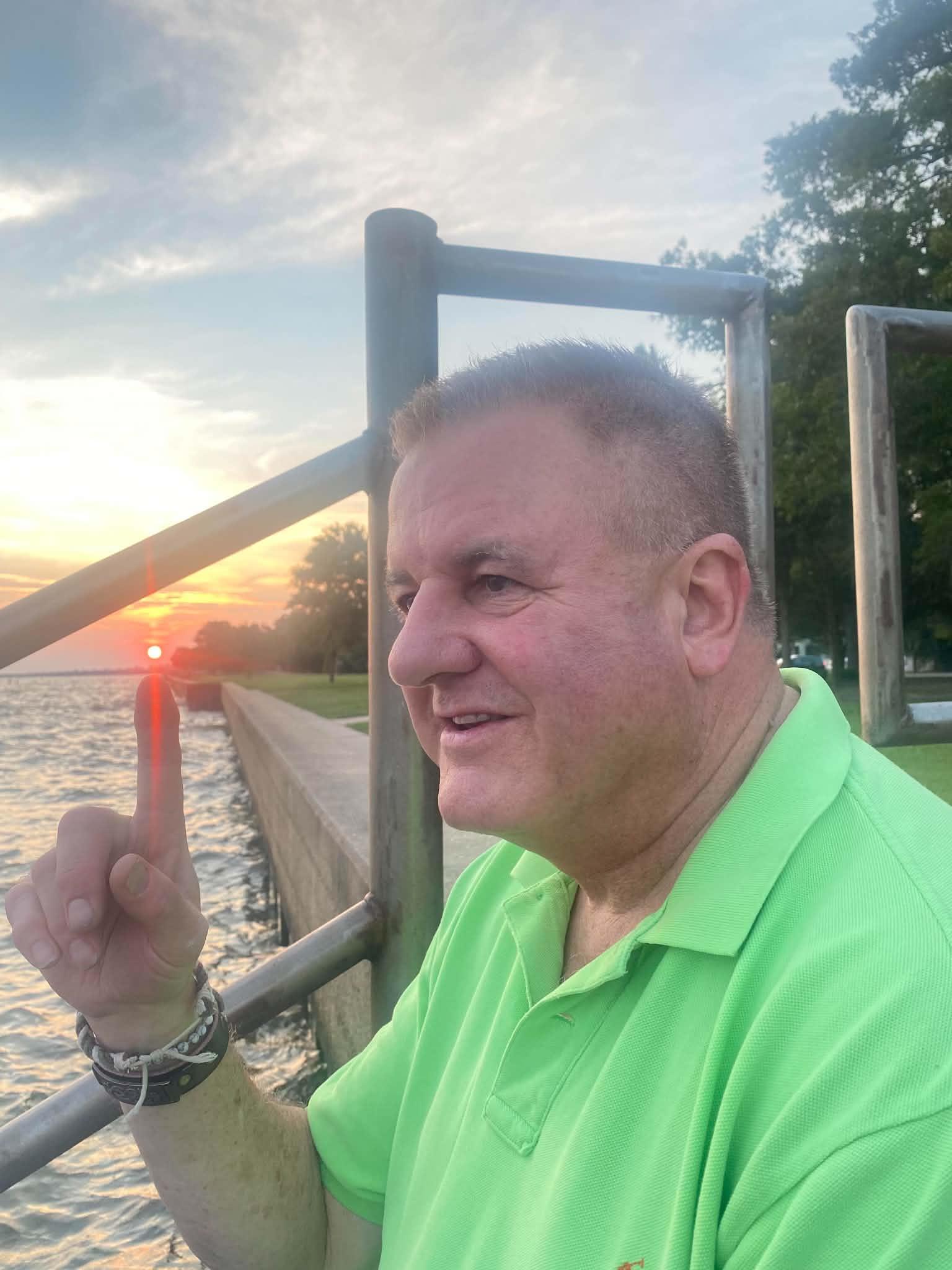A man in a green shirt pointing up with his finger