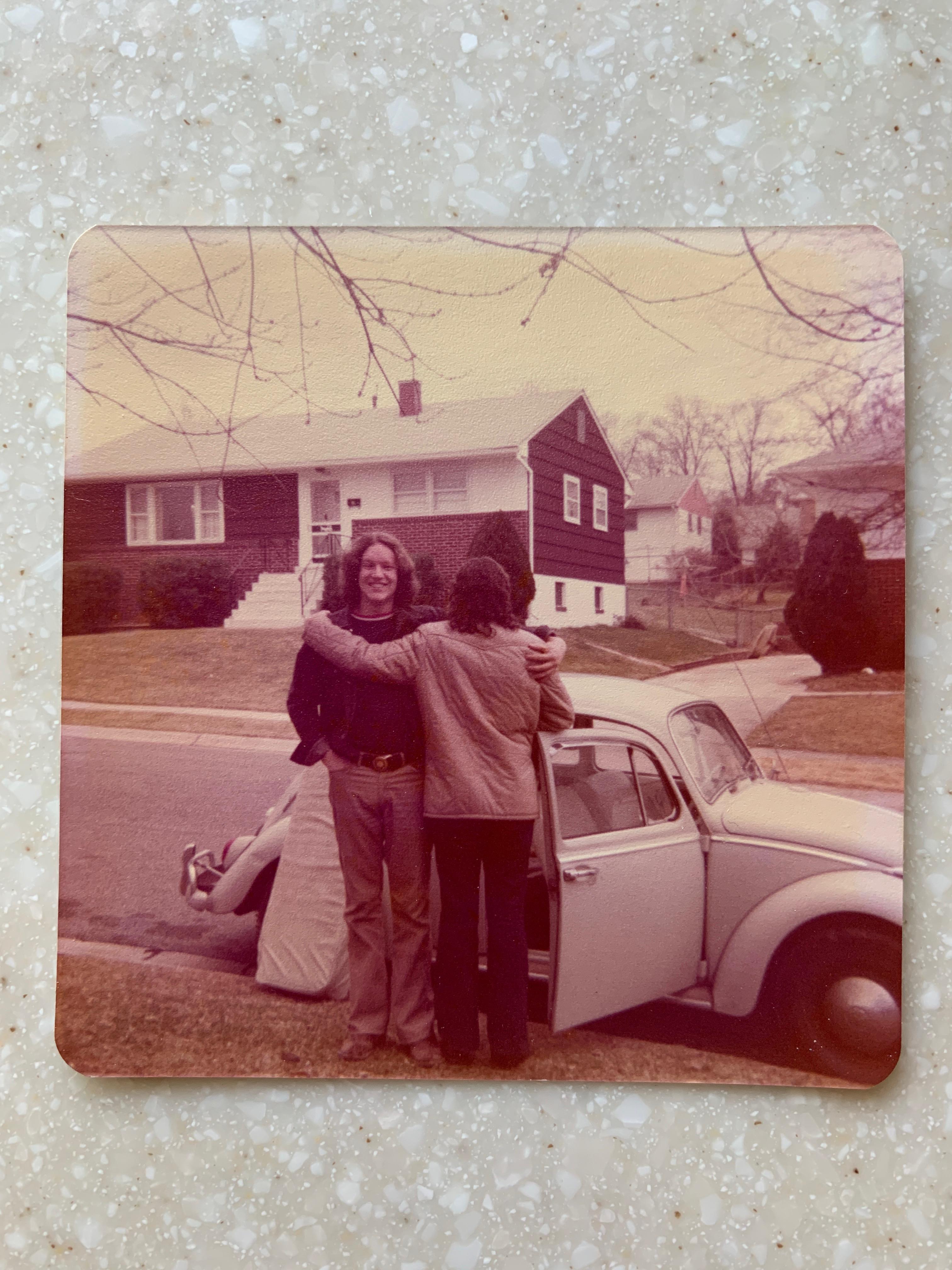 A group of people hugging in front of a car