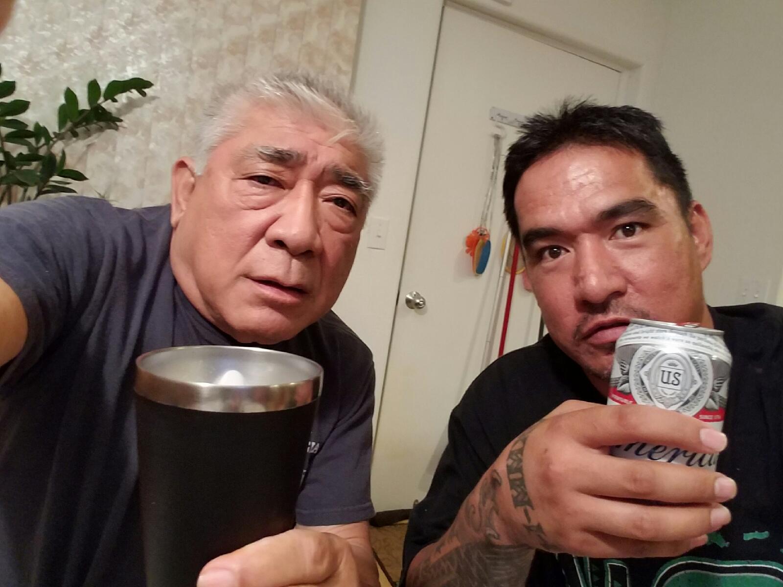 Two men holding cans and a mug