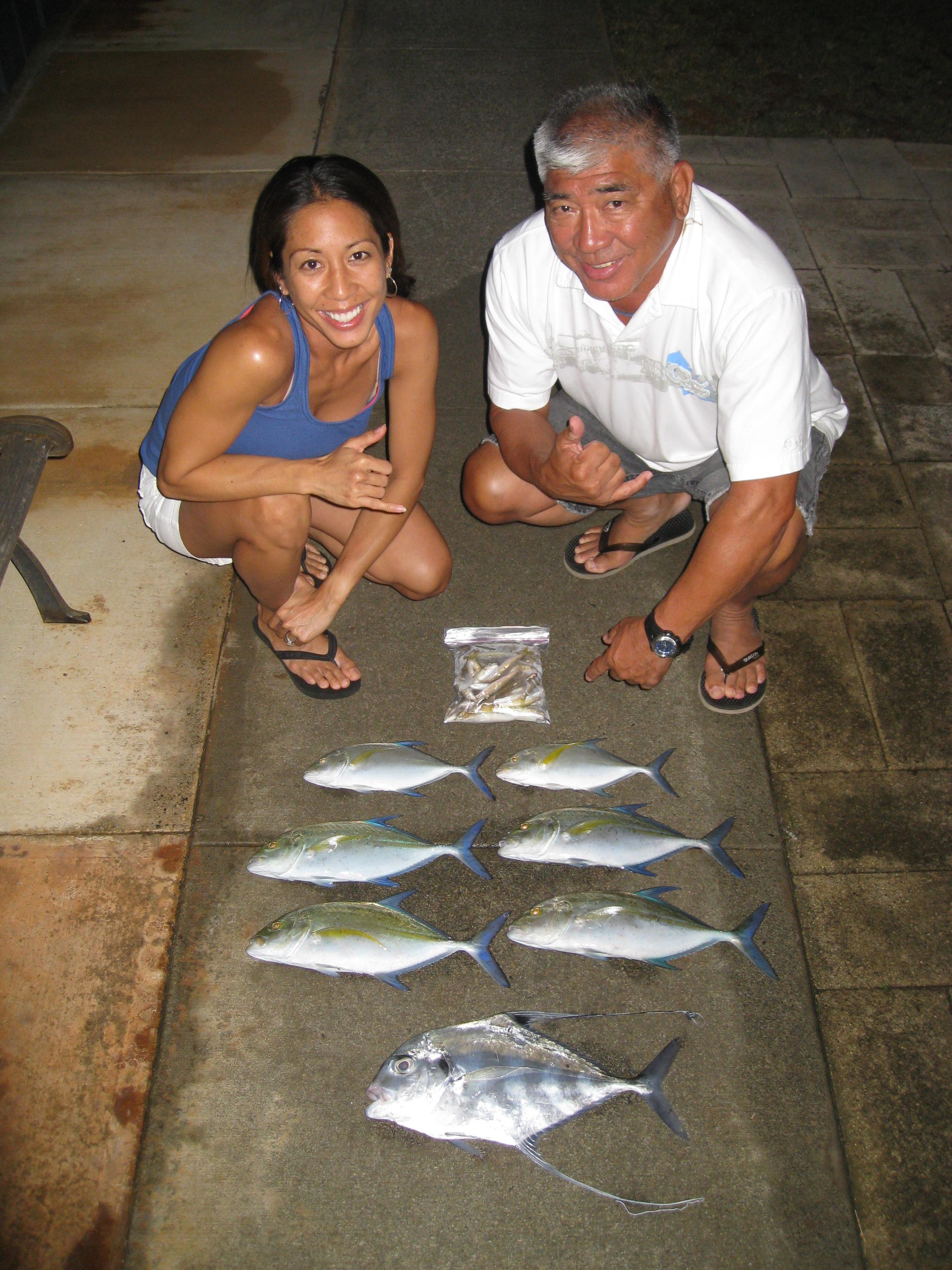 A man and woman kneeling next to several fish