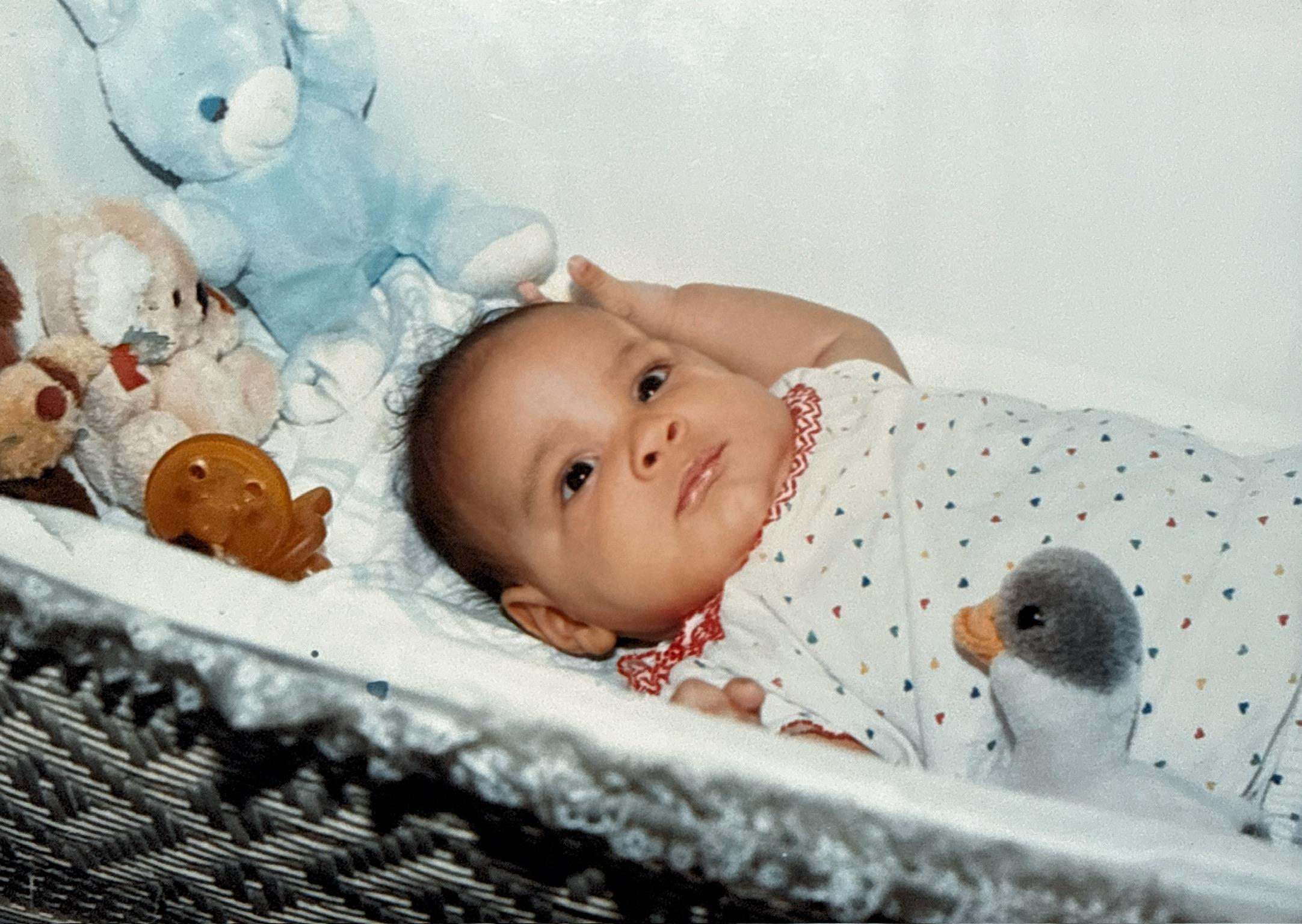 A baby lying in a crib with stuffed animals