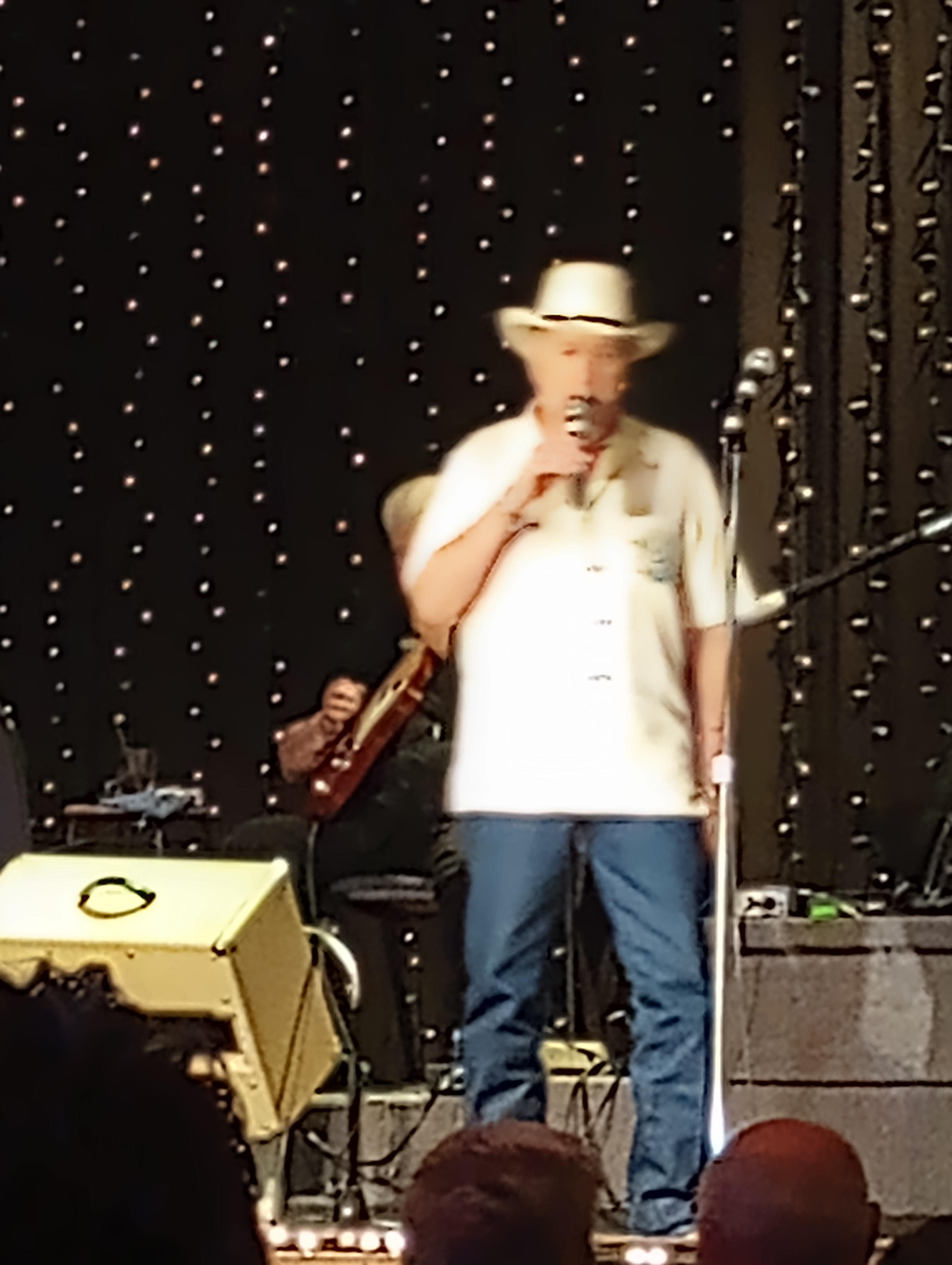 A man on stage with a microphone and a guitar