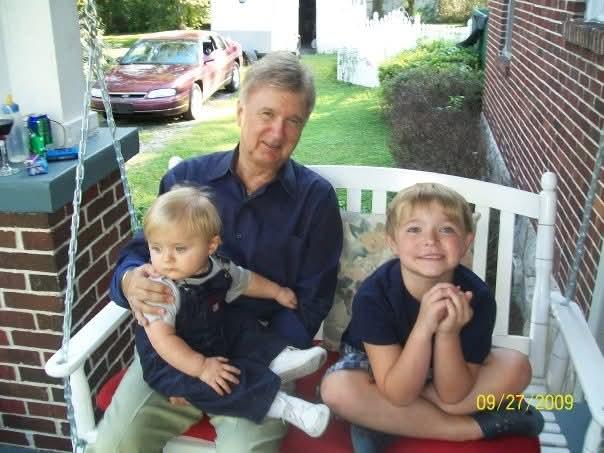 A man holding a baby and a baby sitting on a white bench