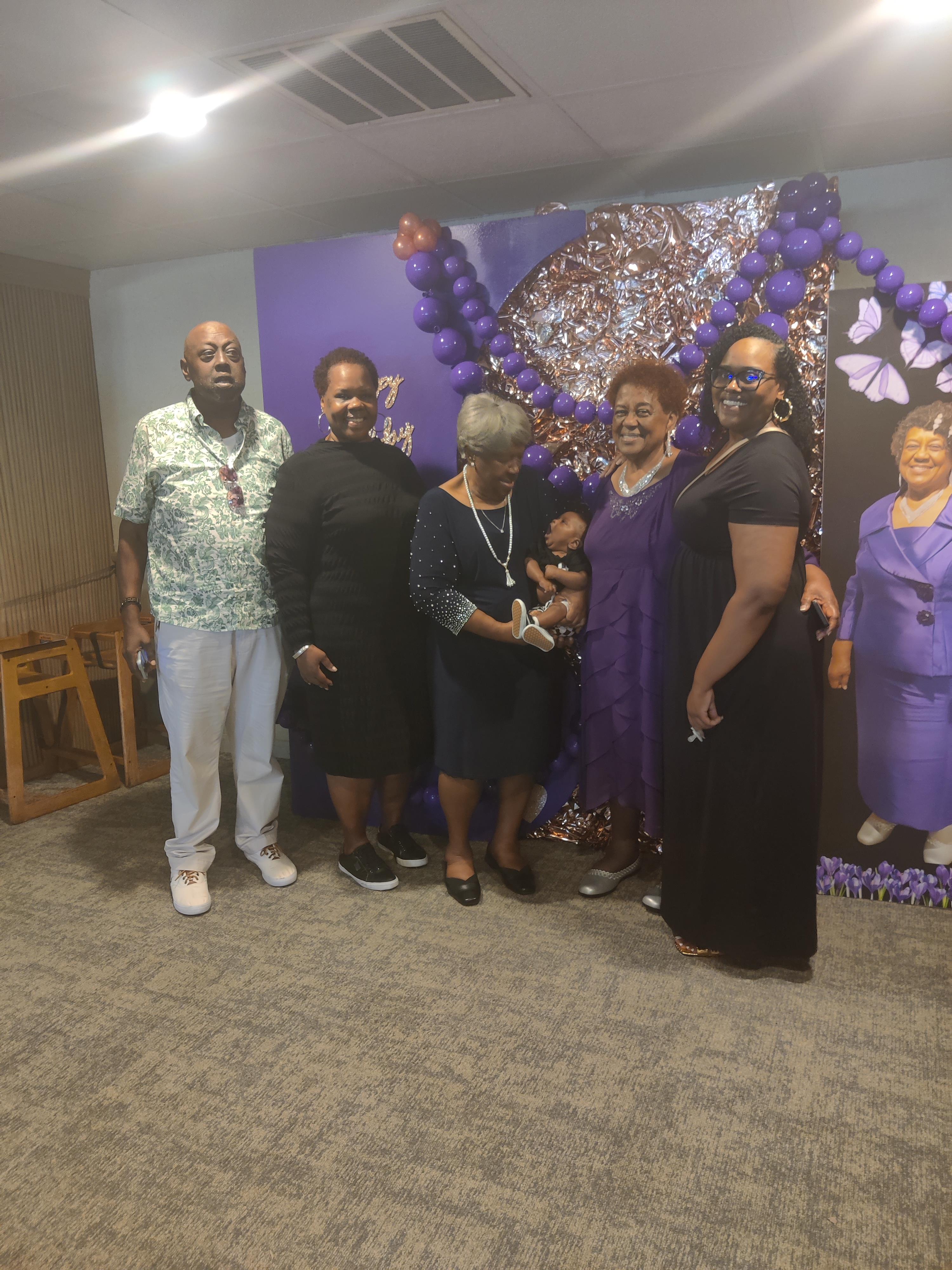 A group of people standing in front of a purple wall
